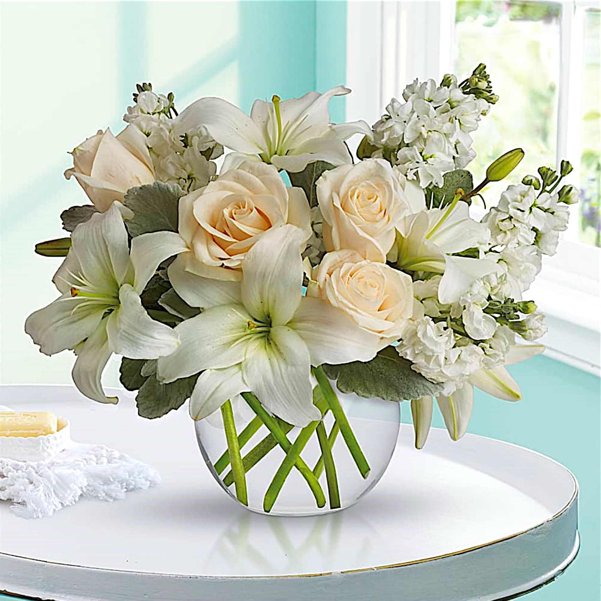 White roses and lilies arranged in a clear glass vase