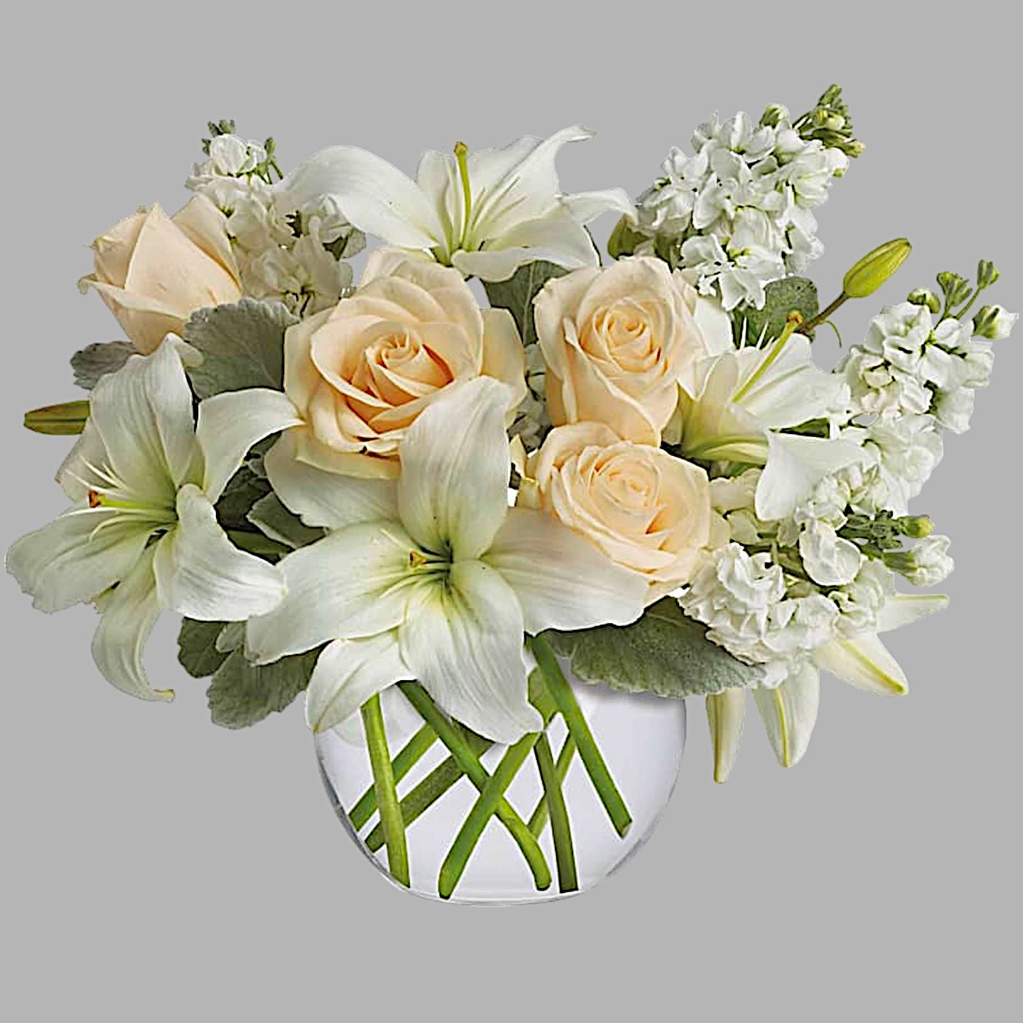 Cream roses and white lilies arranged in a clear glass vase