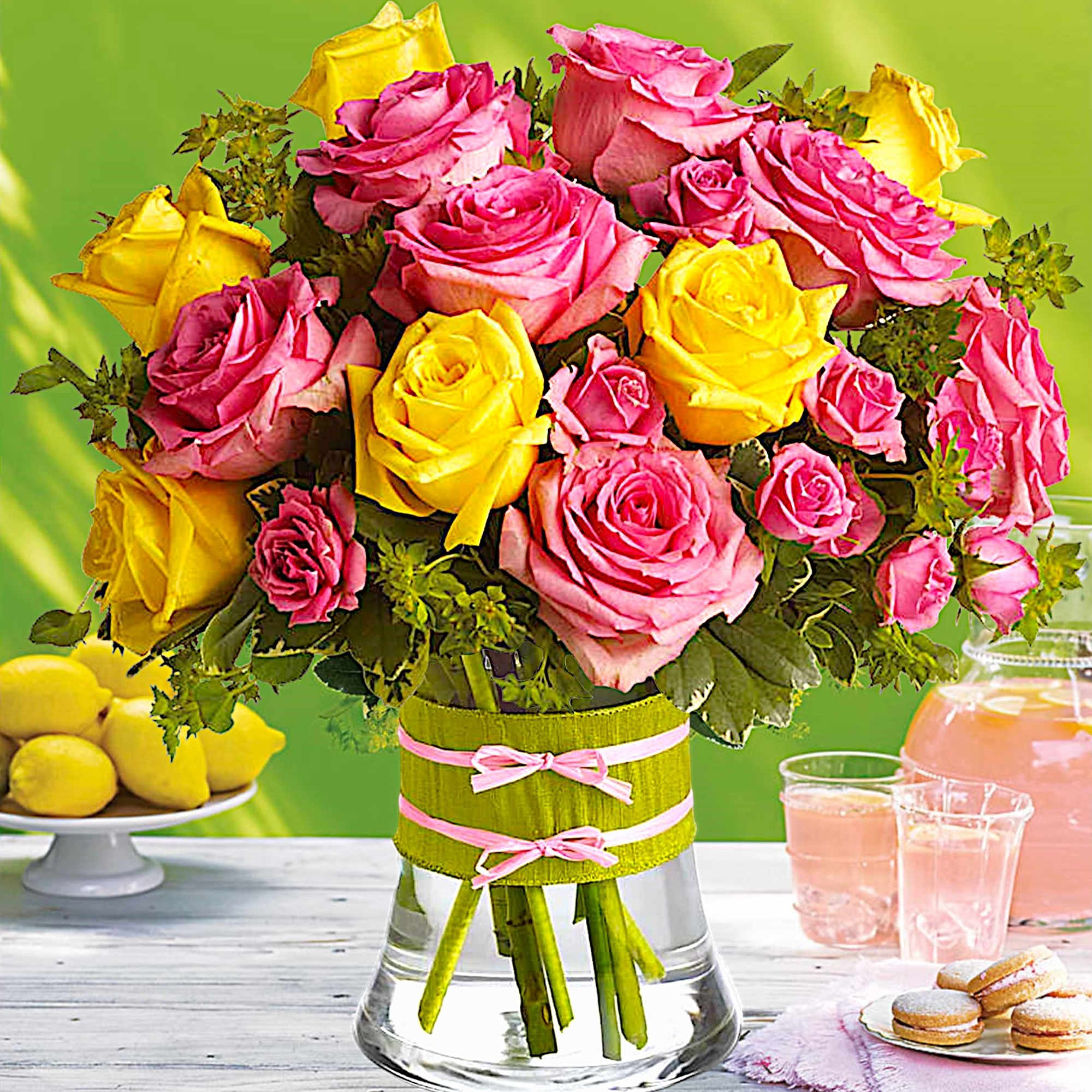 Bouquet of pink and yellow roses in a glass vase with pink ribbon