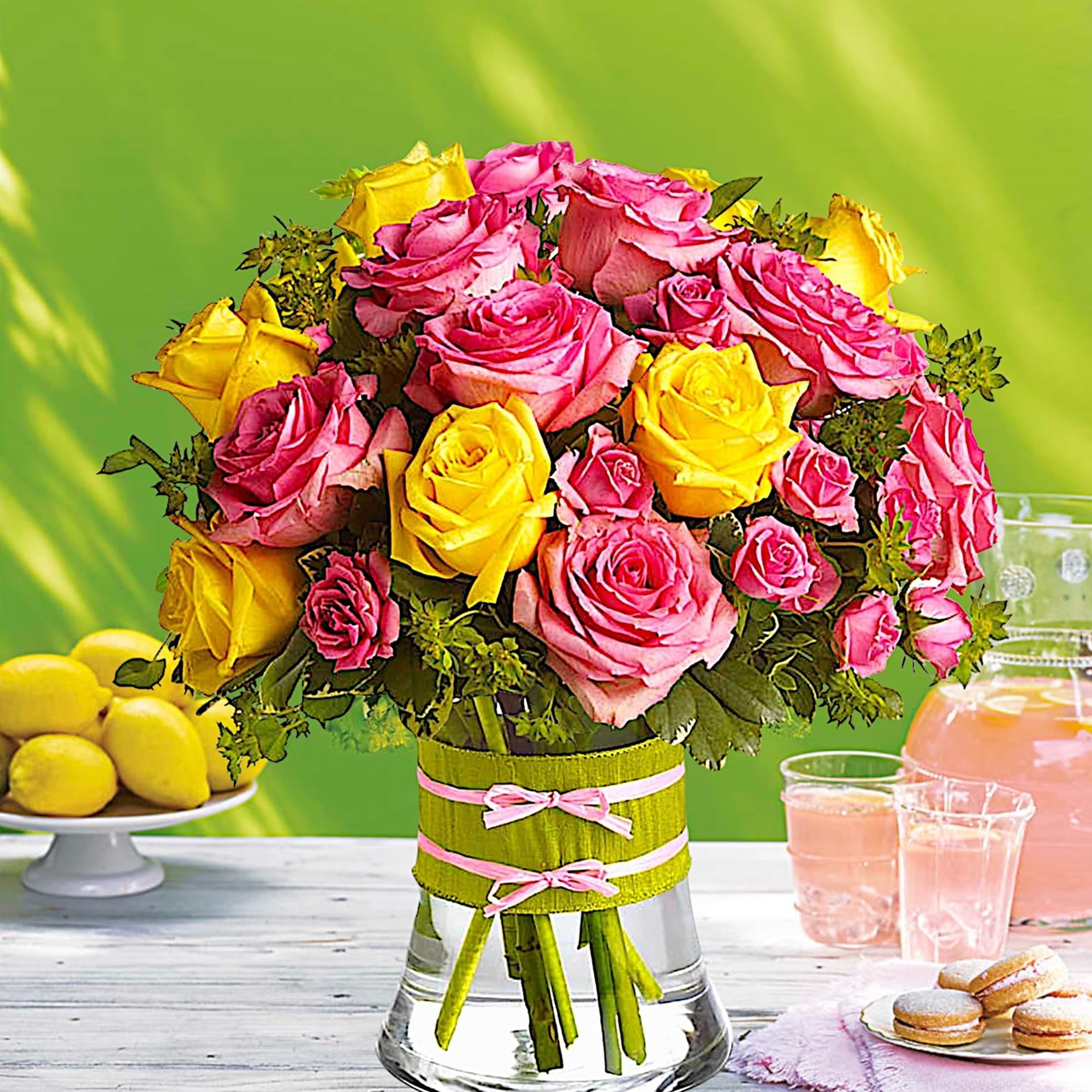 Pink and yellow roses arranged in a clear glass vase with ribbon, photo 2 of 5