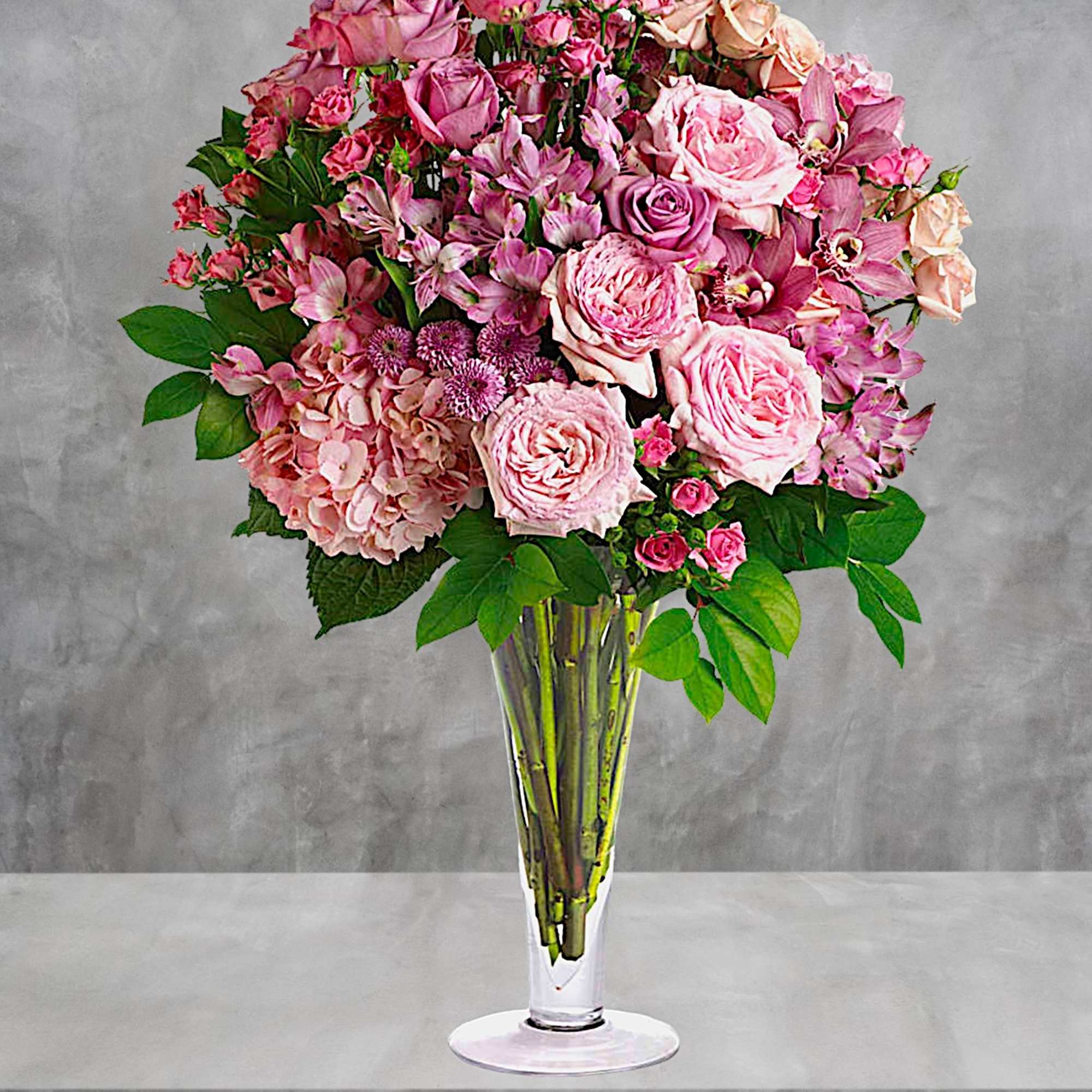 Pink roses and mixed blooms arranged in a clear glass vase
