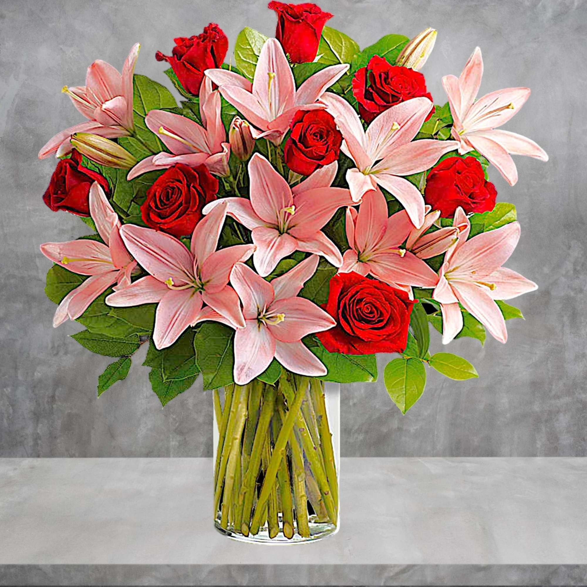 Bouquet of pink lilies and red roses in a clear glass vase