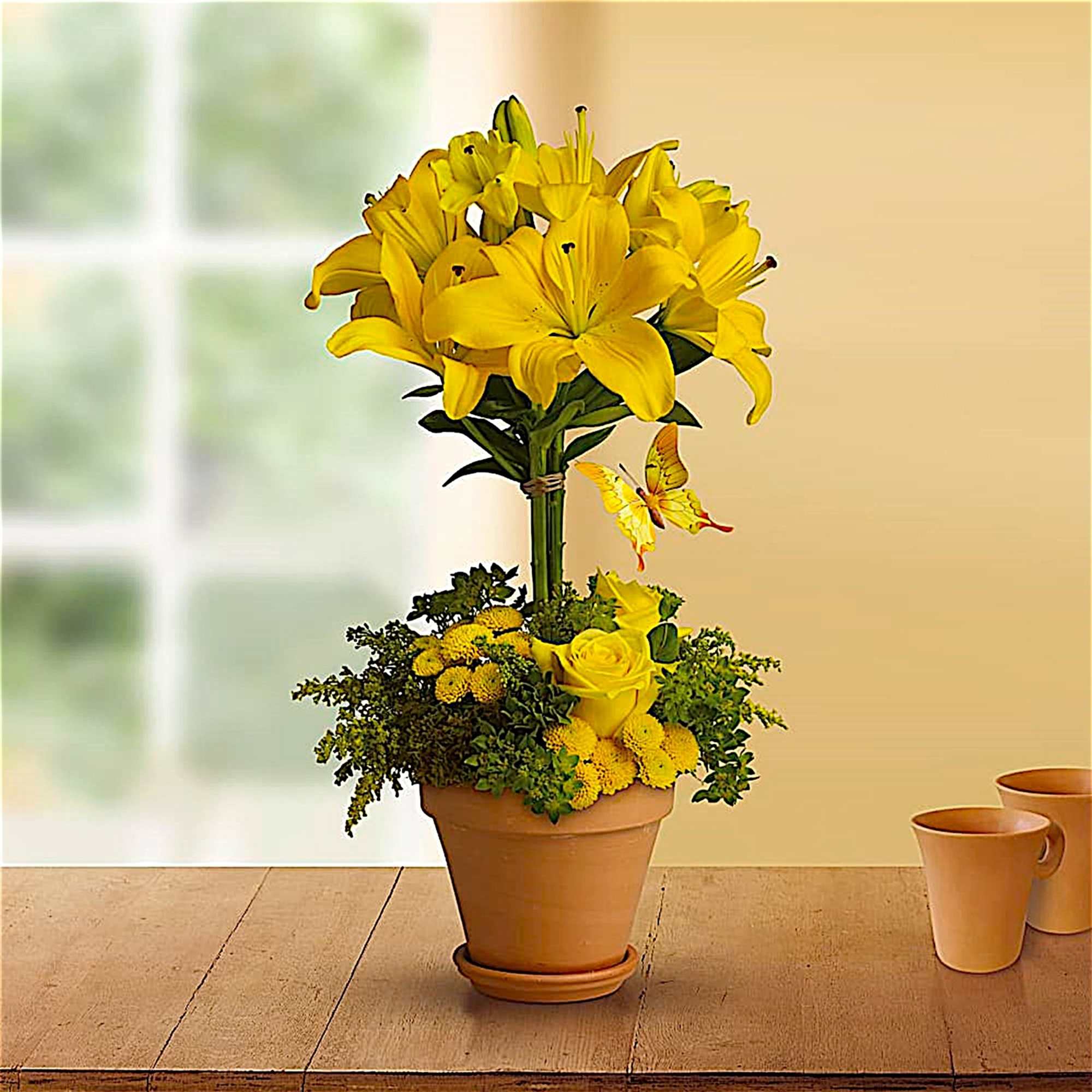 Yellow lily arrangement in a terracotta pot with a butterfly accent