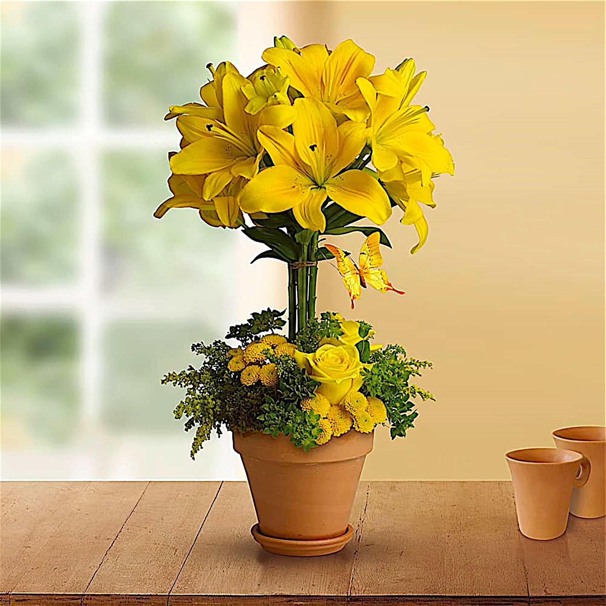 Tall yellow flower arrangement in a terracotta pot with a butterfly accent