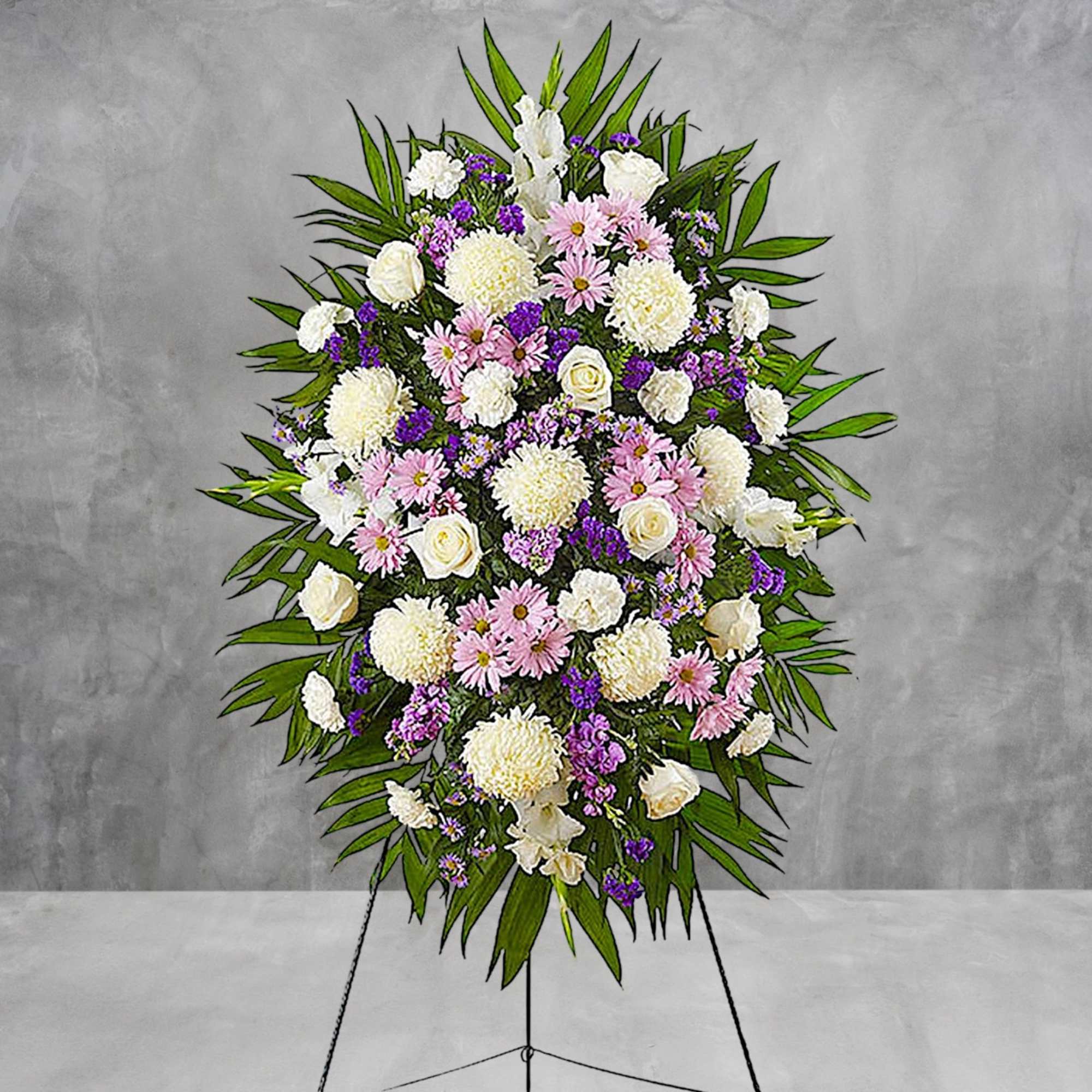 Standing funeral spray of white, pink, and purple flowers on an easel