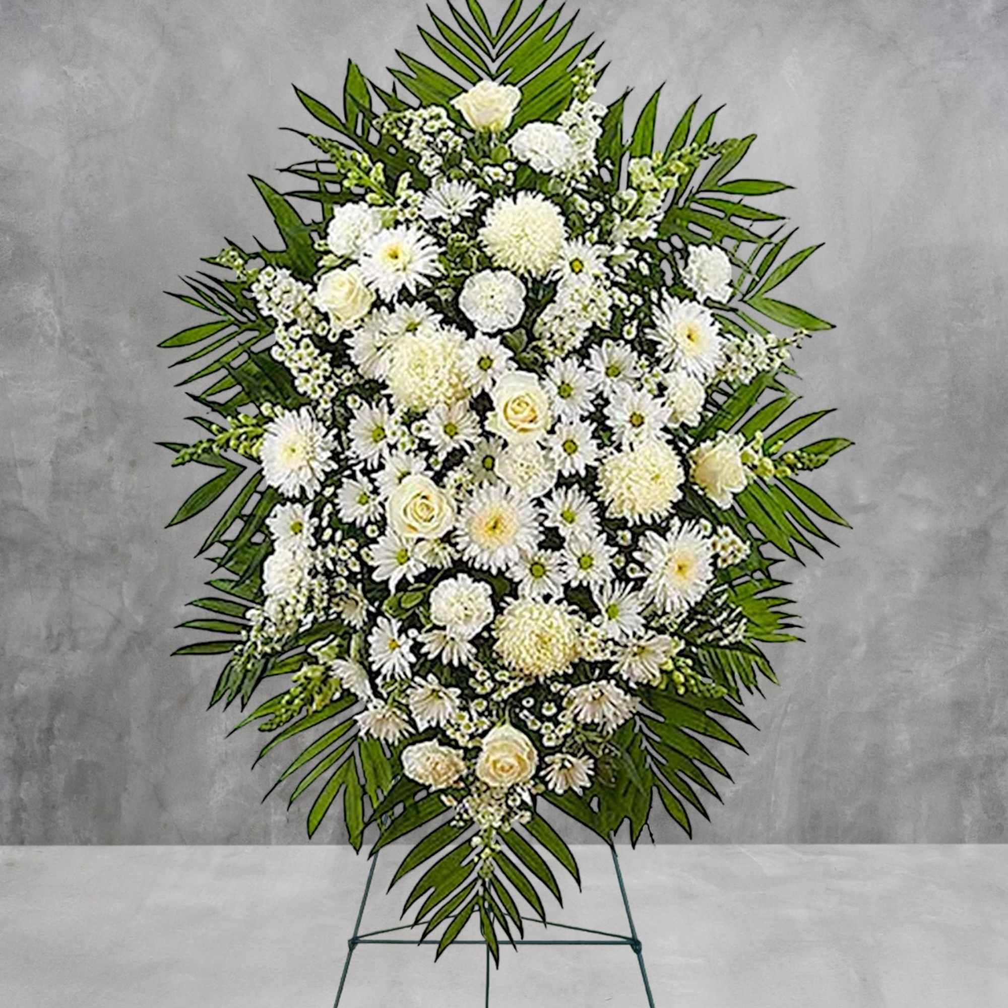 White floral funeral spray on a standing easel with palm leaves
