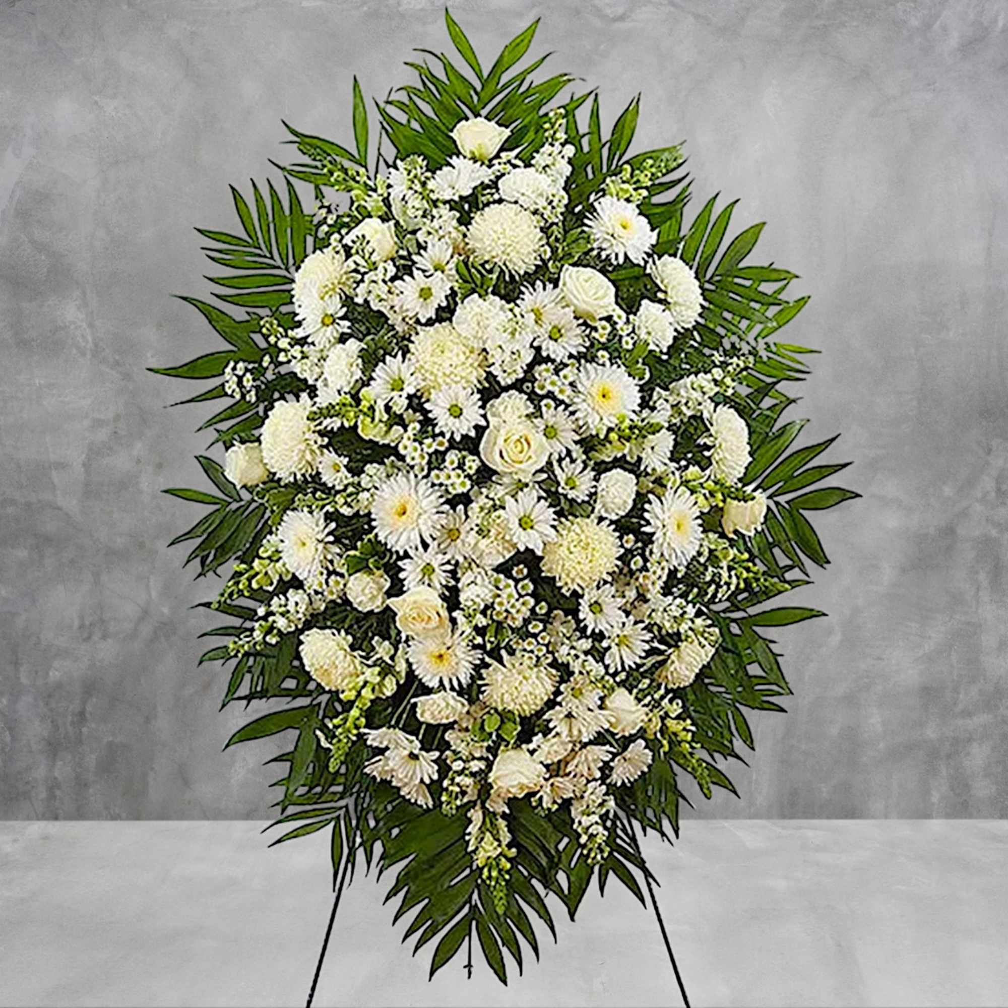 Large white funeral spray with mixed blooms on a standing easel