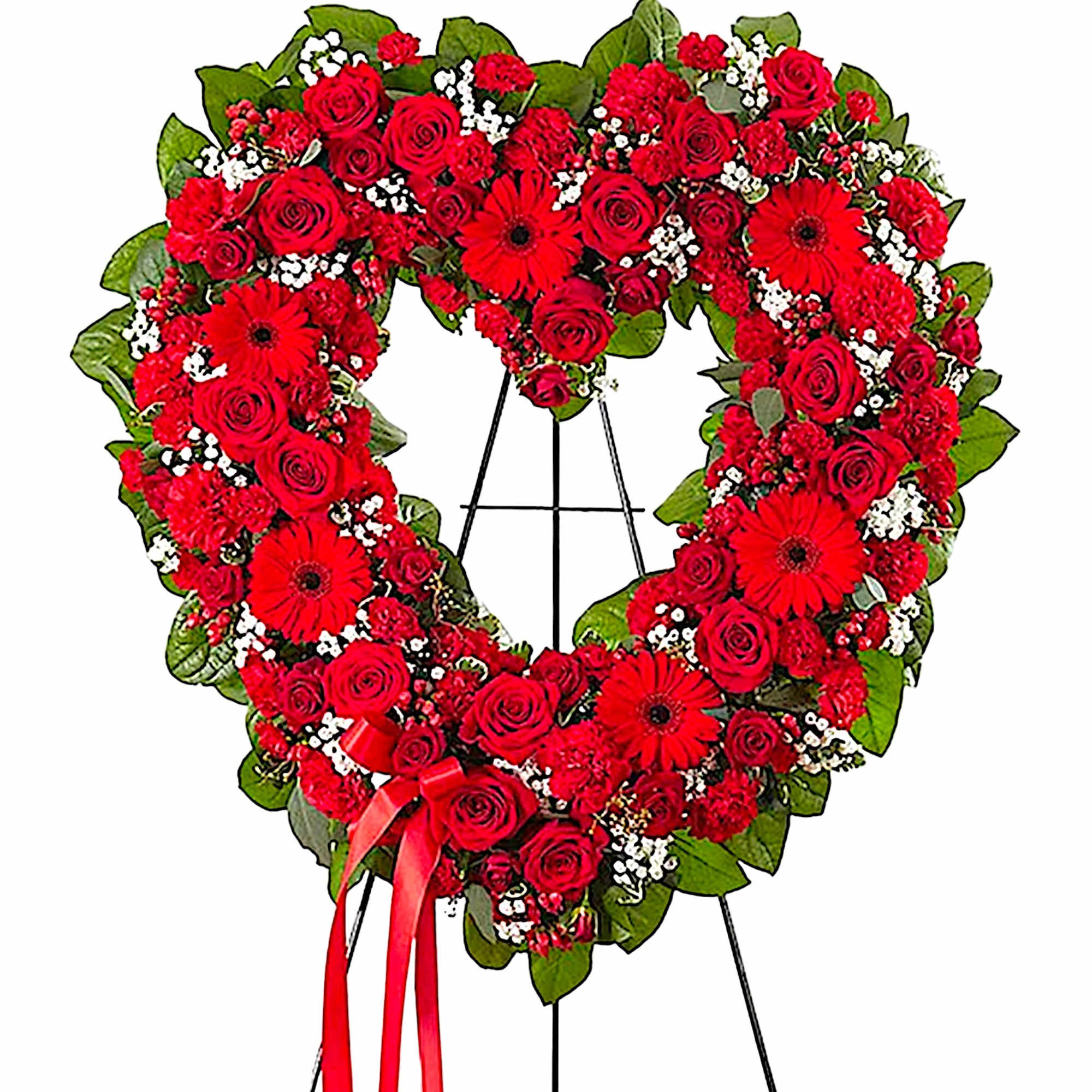Heart-shaped red rose wreath on a black easel with a red ribbon