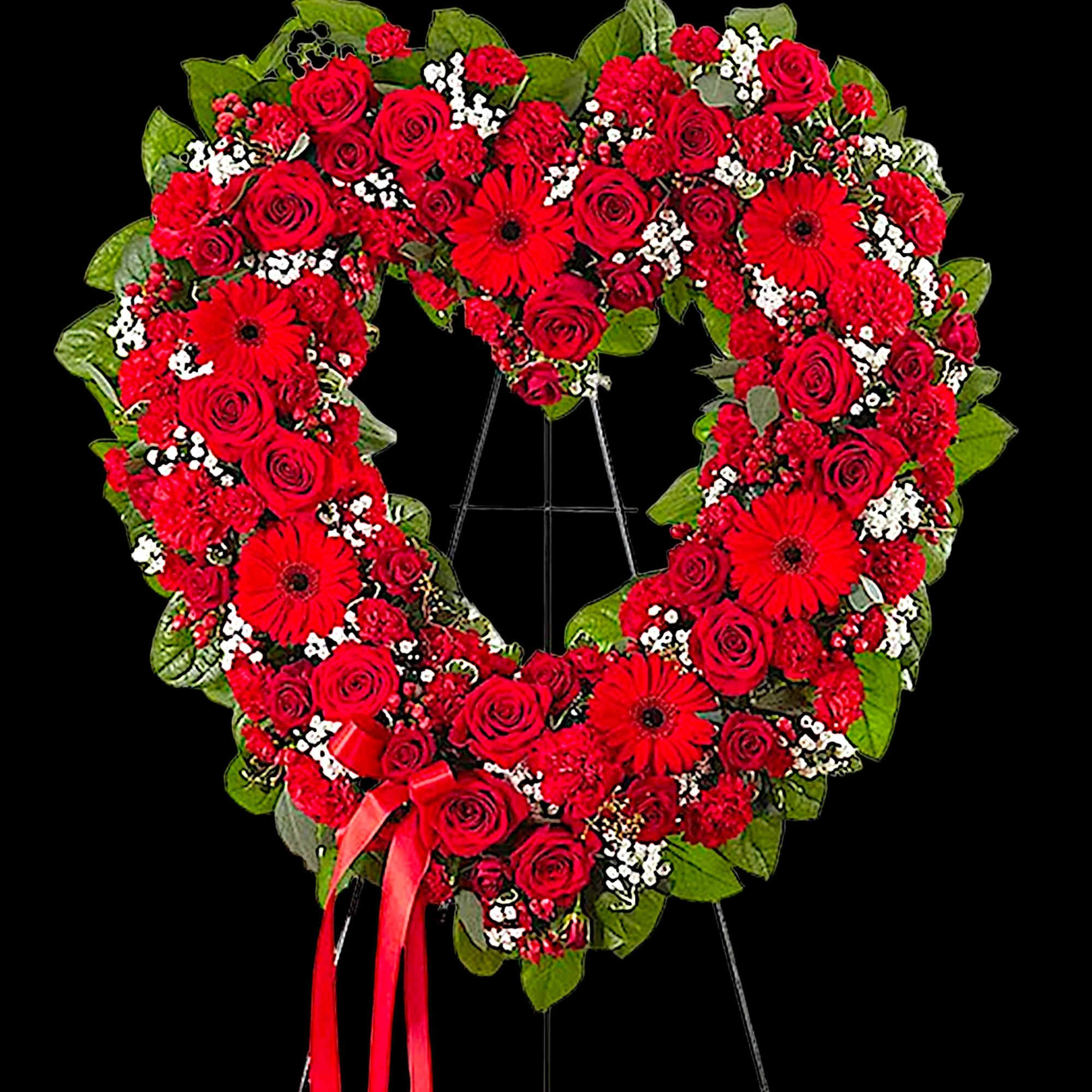 Heart-shaped red rose funeral wreath on an easel with a ribbon