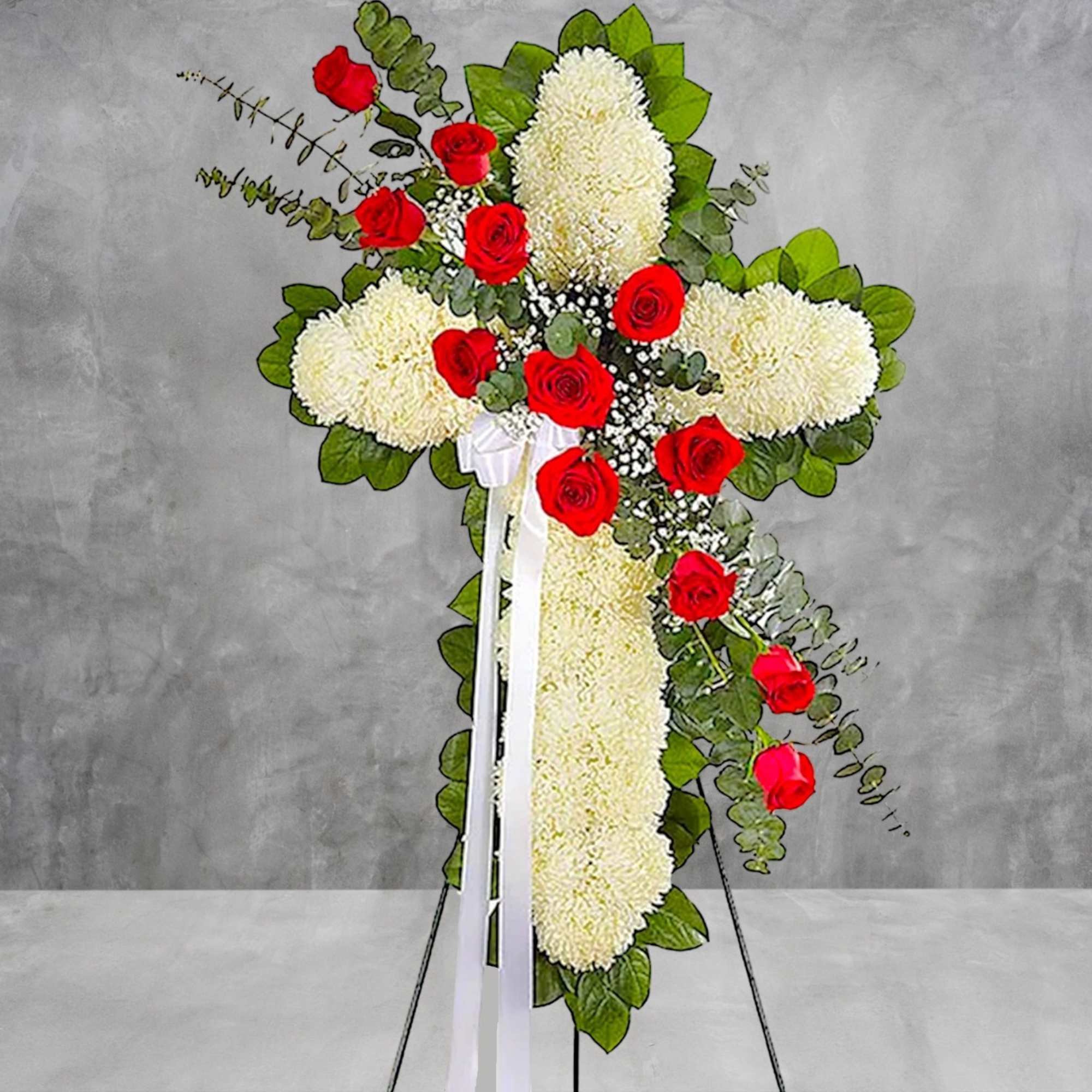 Standing floral cross with white mums and red roses on a white ribbon