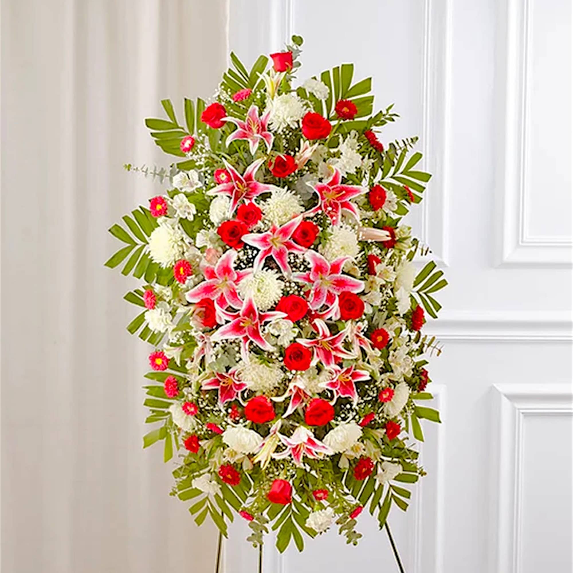 Standing floral spray with red and white flowers on a metal easel