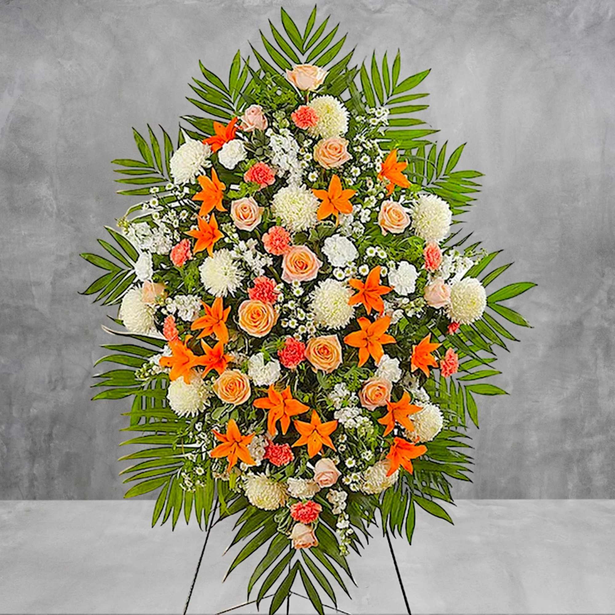 Standing floral spray with orange and peach flowers on a tripod easel