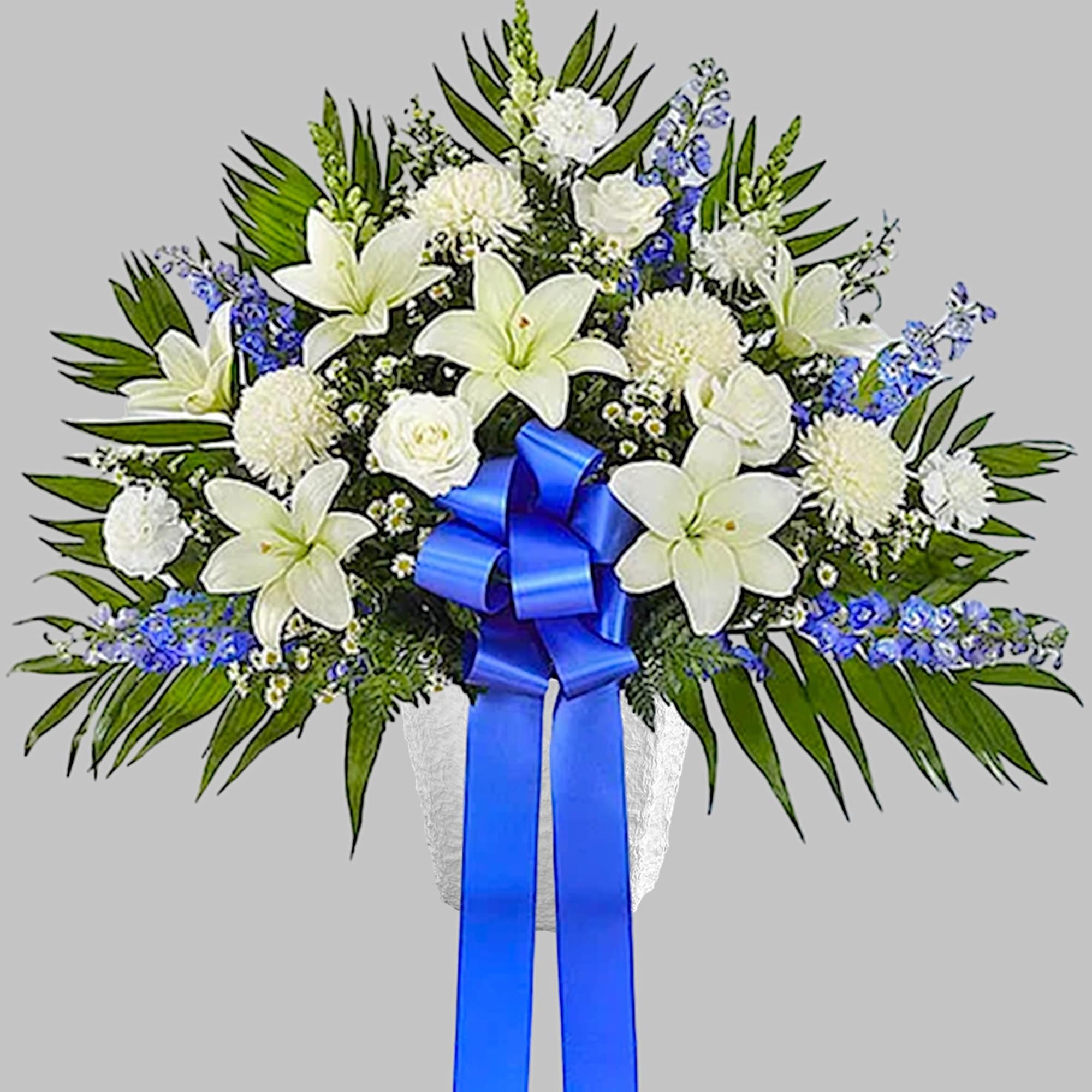 White lilies and blue flowers in a vase with a blue ribbon