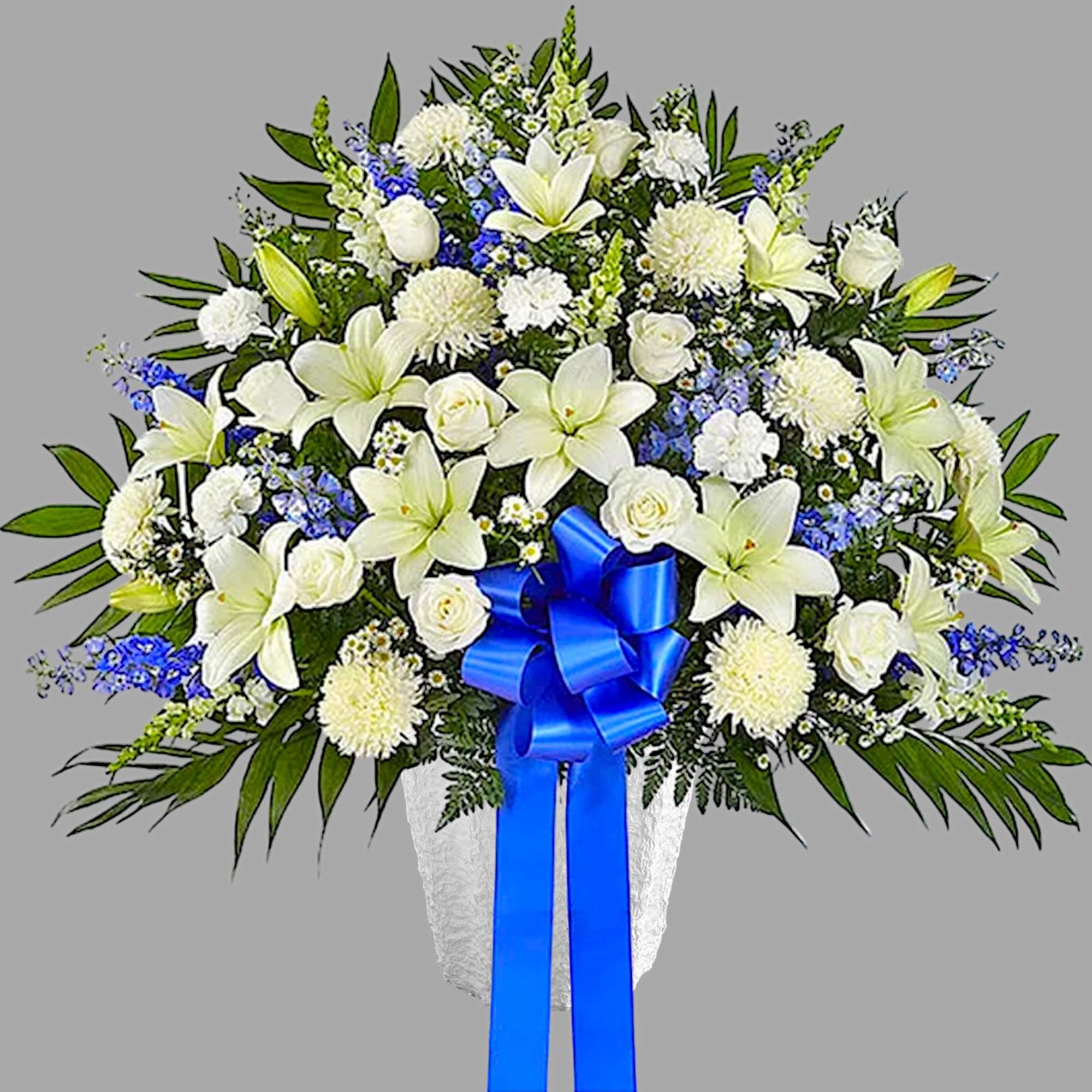 White lilies and roses in a white vase with a blue ribbon