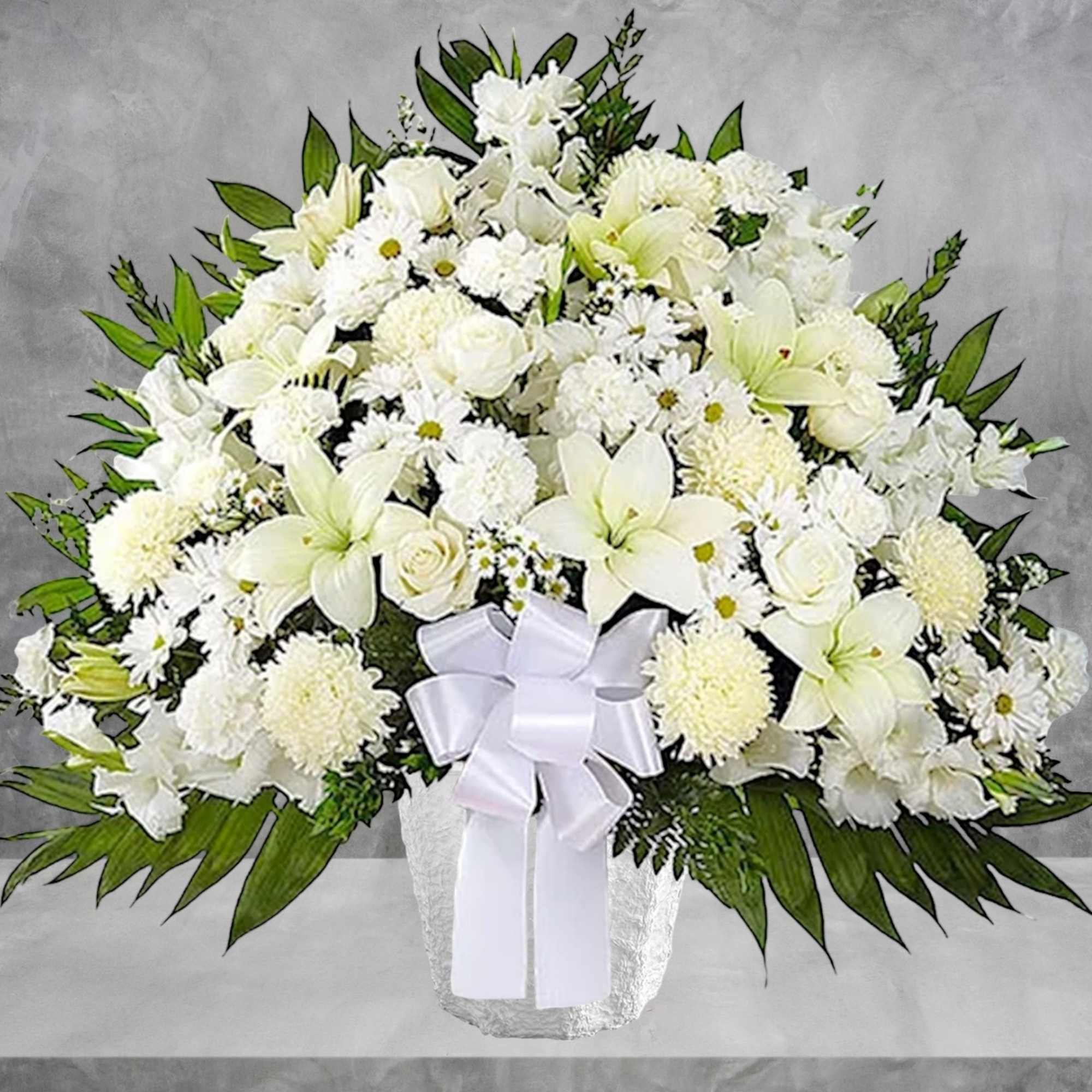 White floral arrangement in a textured vase with a white ribbon