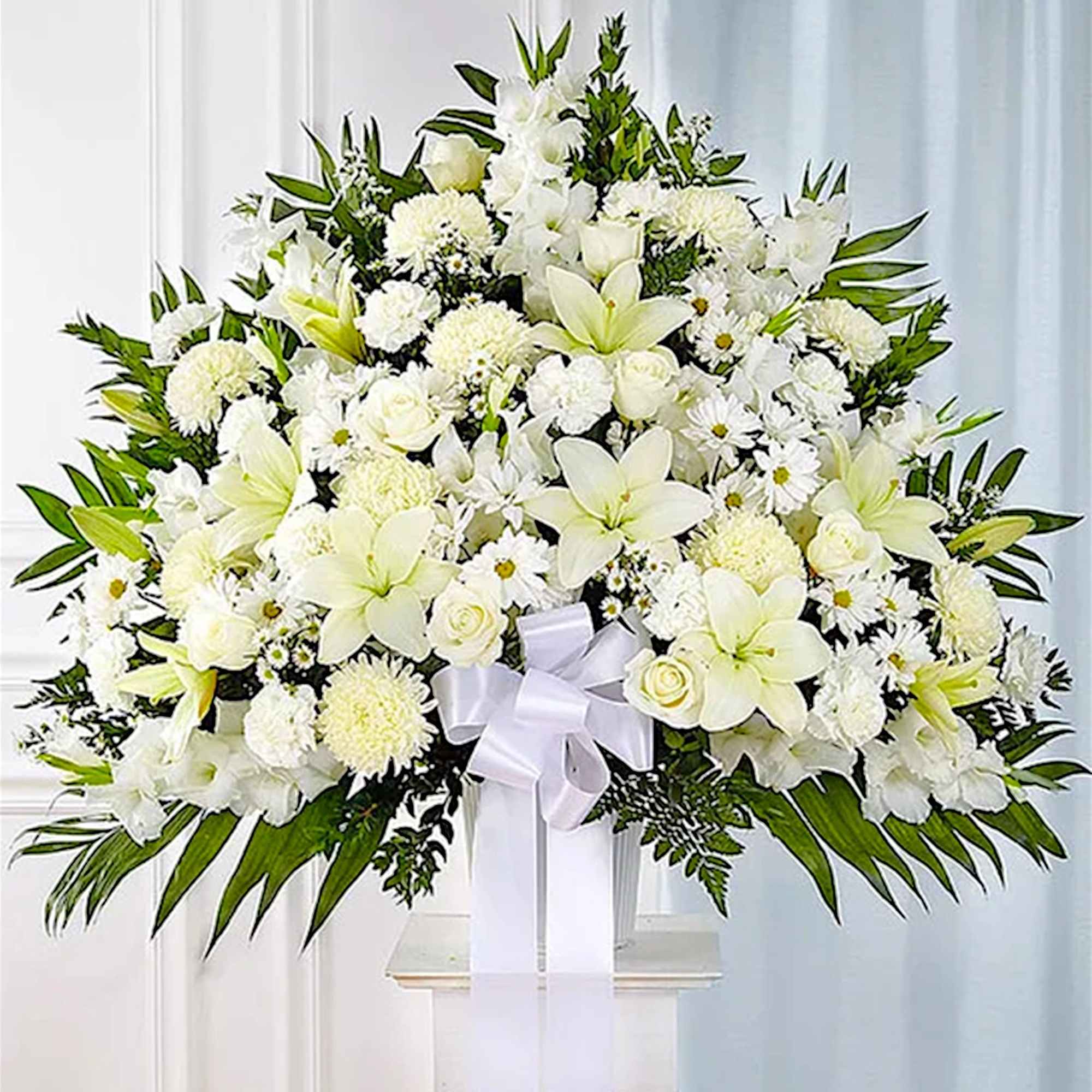 Large white funeral spray with lilies, roses, and chrysanthemums on a stand
