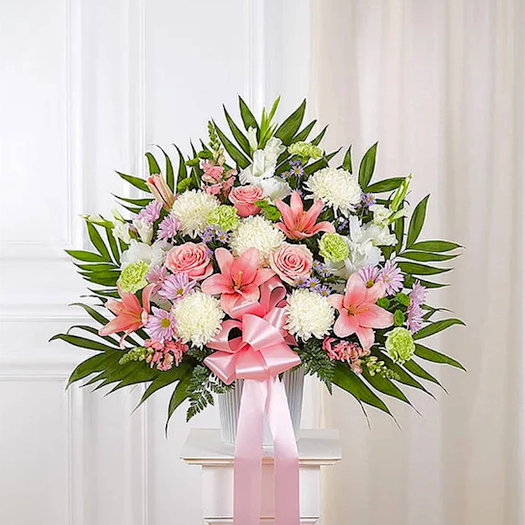 Large pink and white floral standing arrangement with a pink ribbon