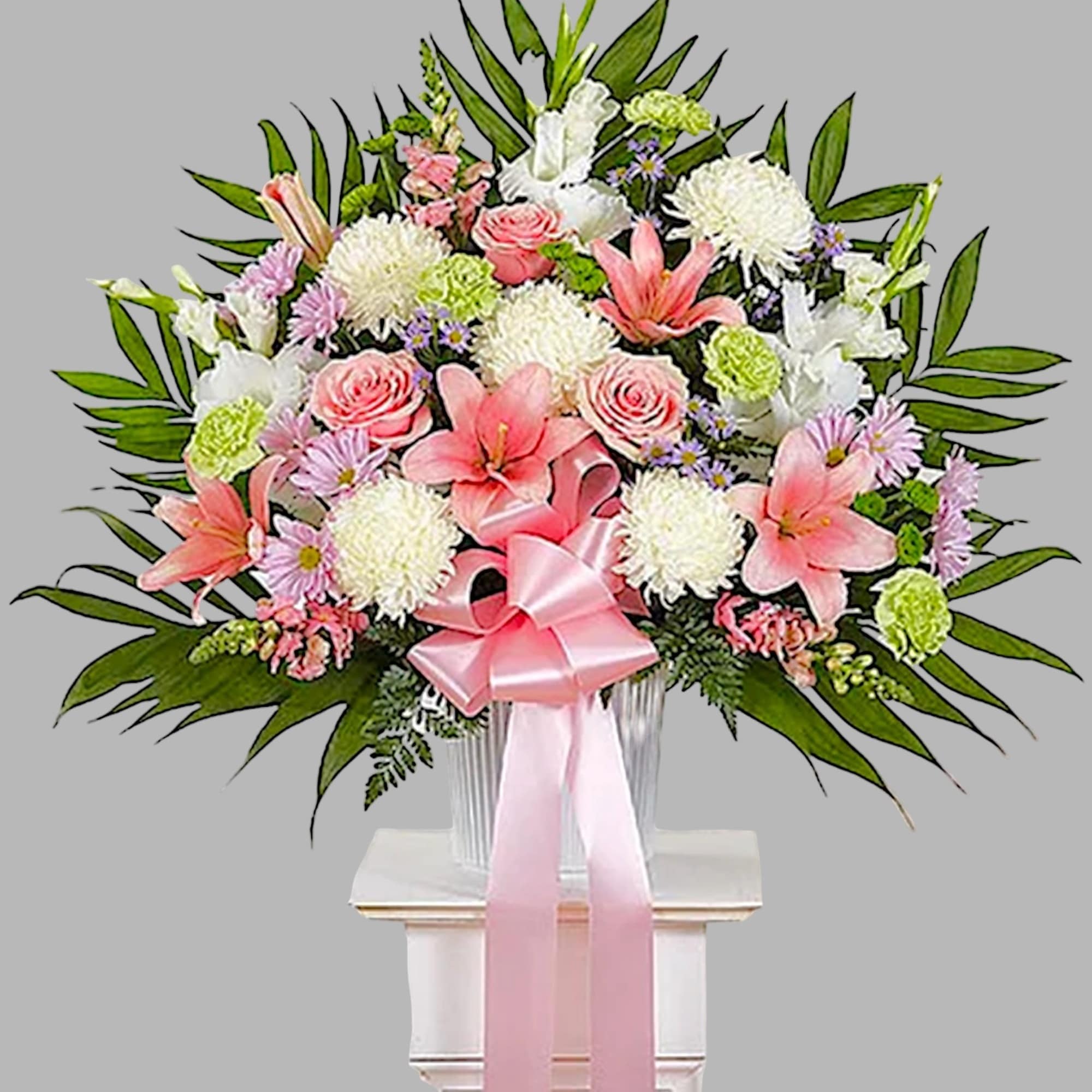 Pink and white floral spray in a clear vase with a pink ribbon