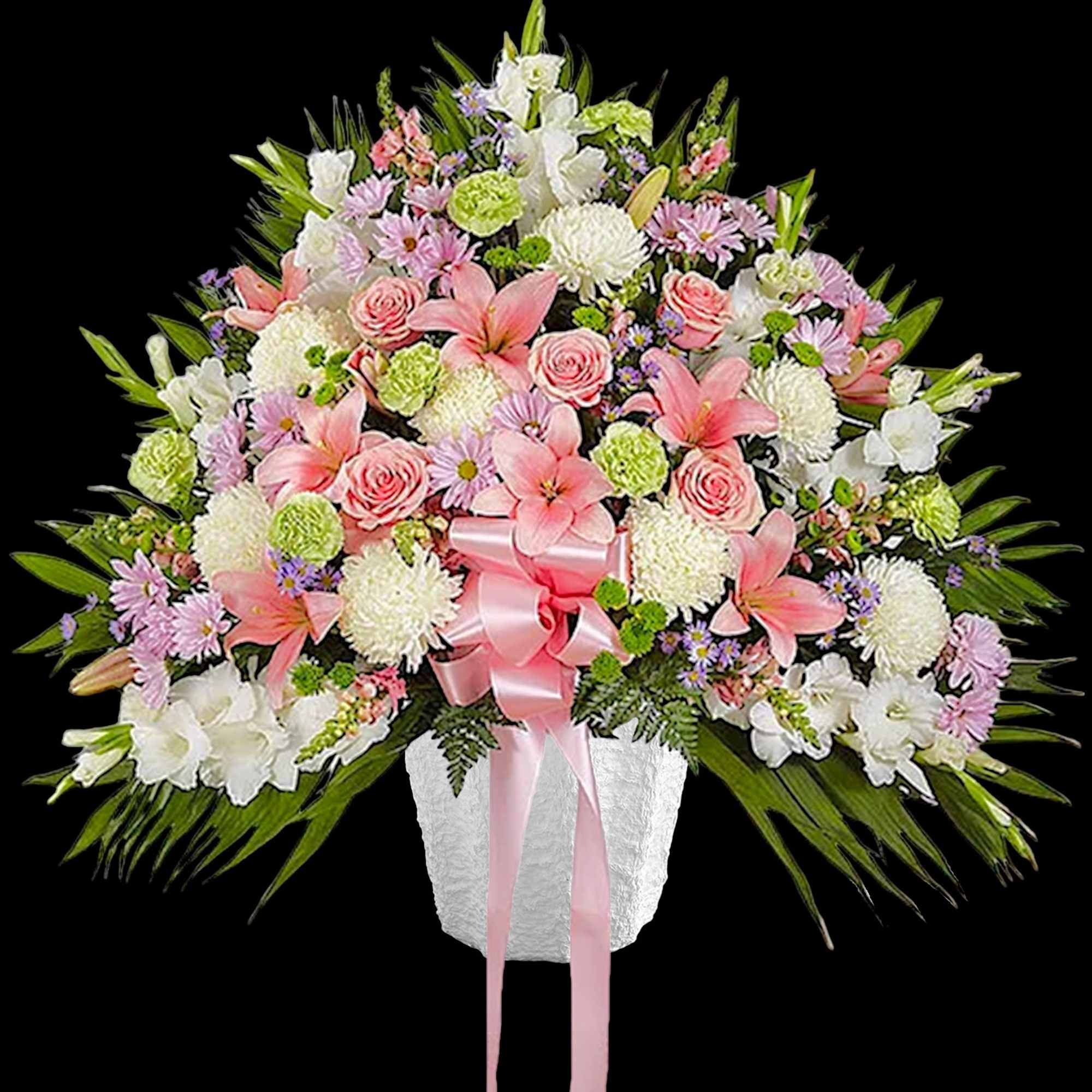 Large pink and white floral arrangement in a white vase with a pink ribbon