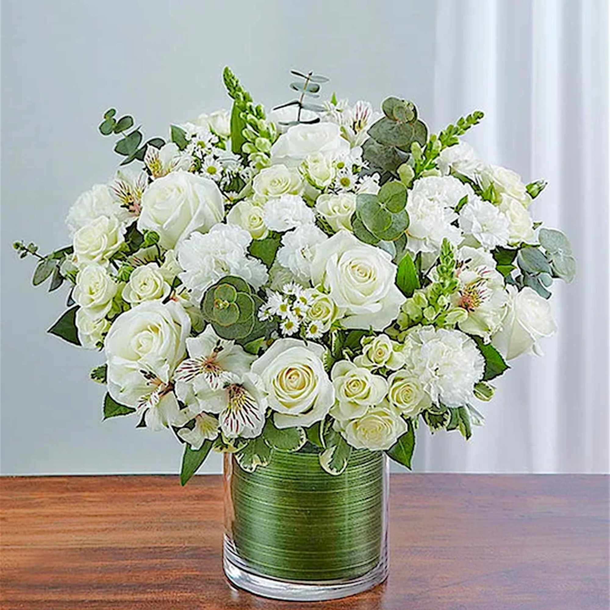 White rose bouquet in a glass vase with green ribbon wrap