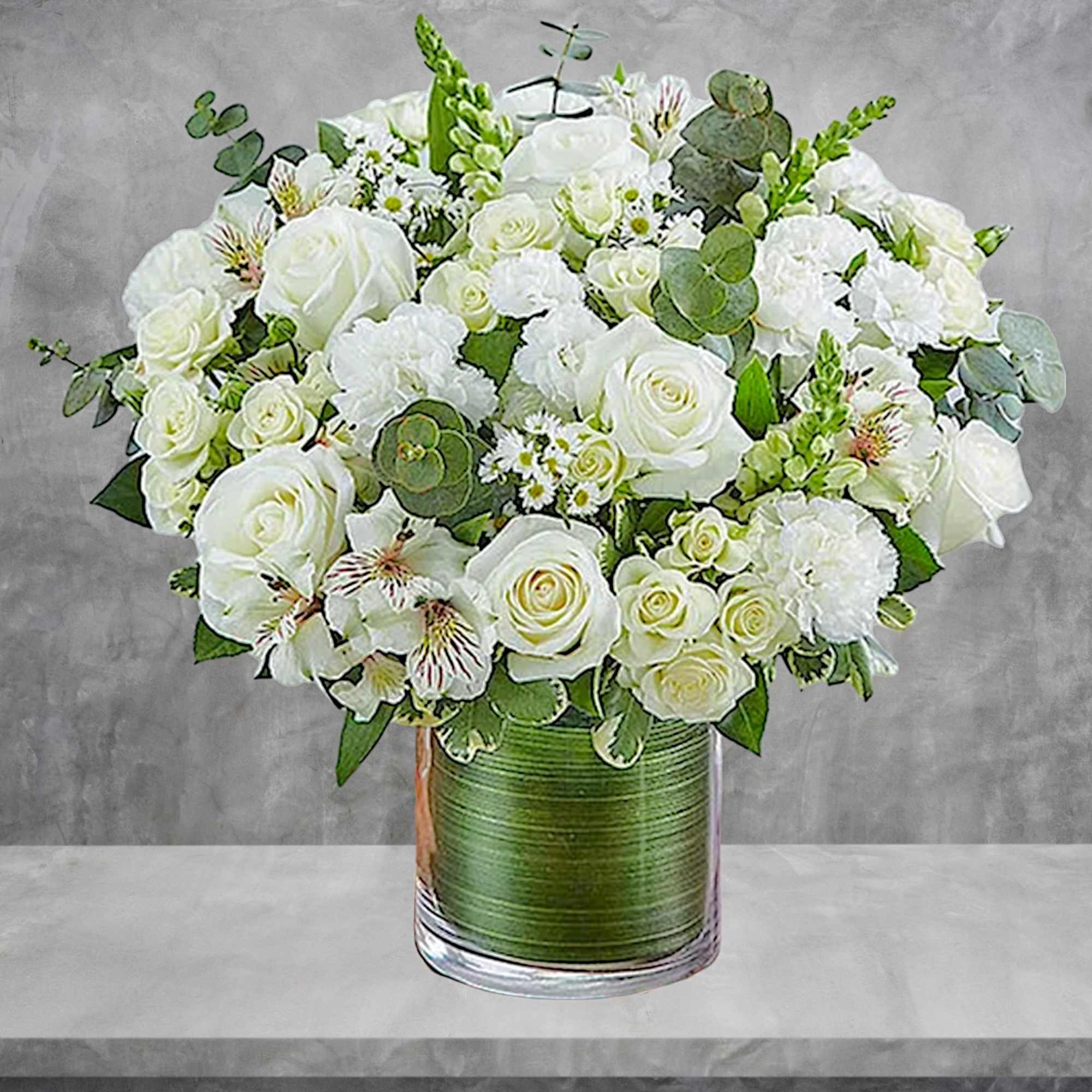White rose bouquet in a clear glass vase with green accents