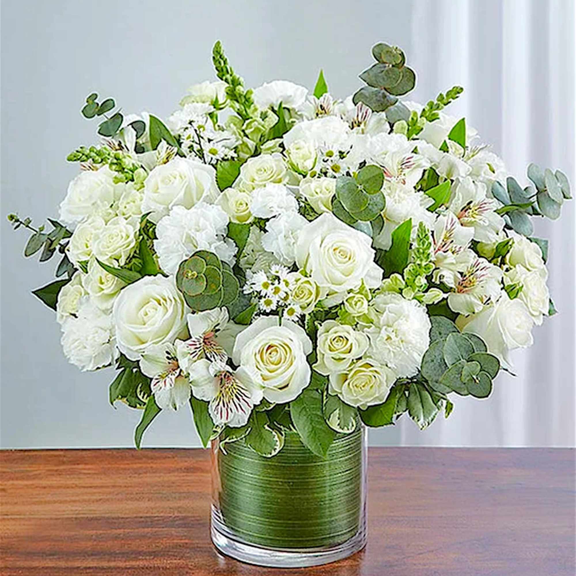 White rose bouquet in a glass vase with eucalyptus