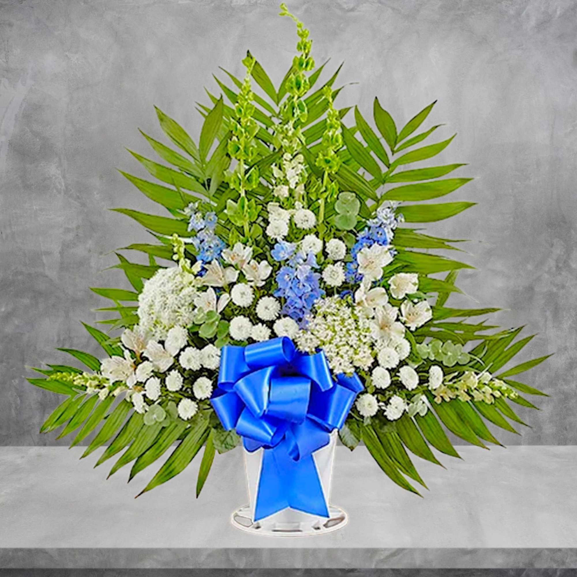 Standing floral spray with white and blue flowers and a large blue ribbon