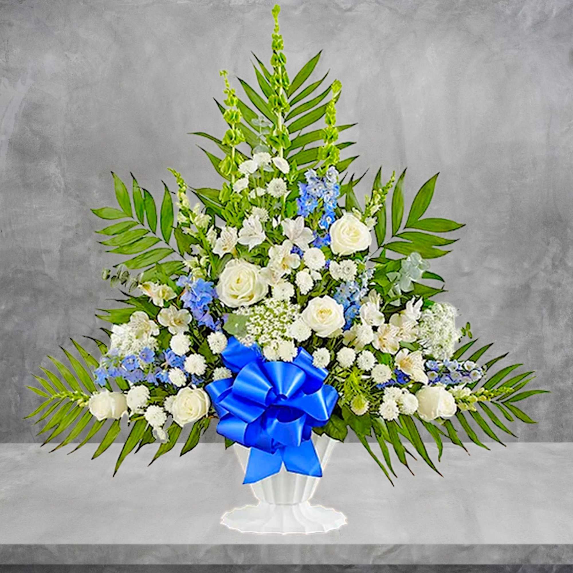 White and blue floral standing arrangement in a white urn with a blue bow, photo 4 of 6