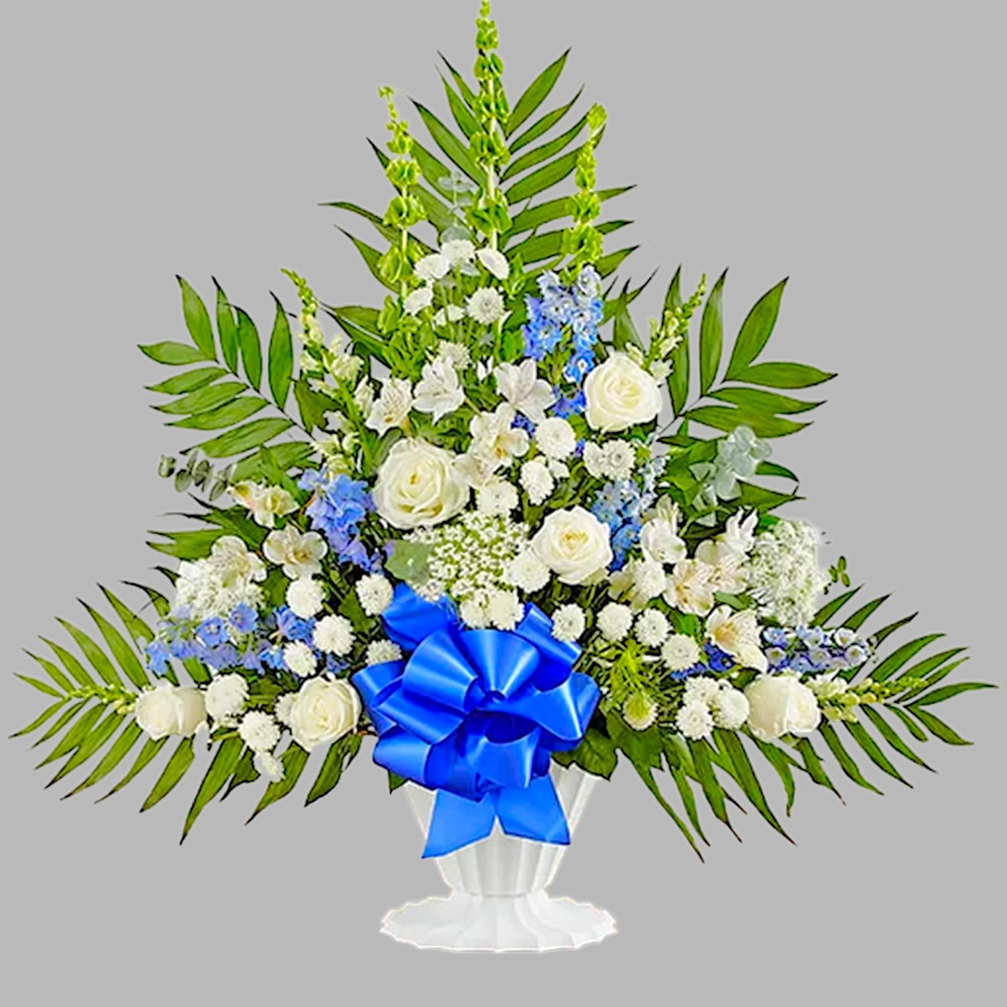 White and blue floral arrangement in a white vase with a blue ribbon