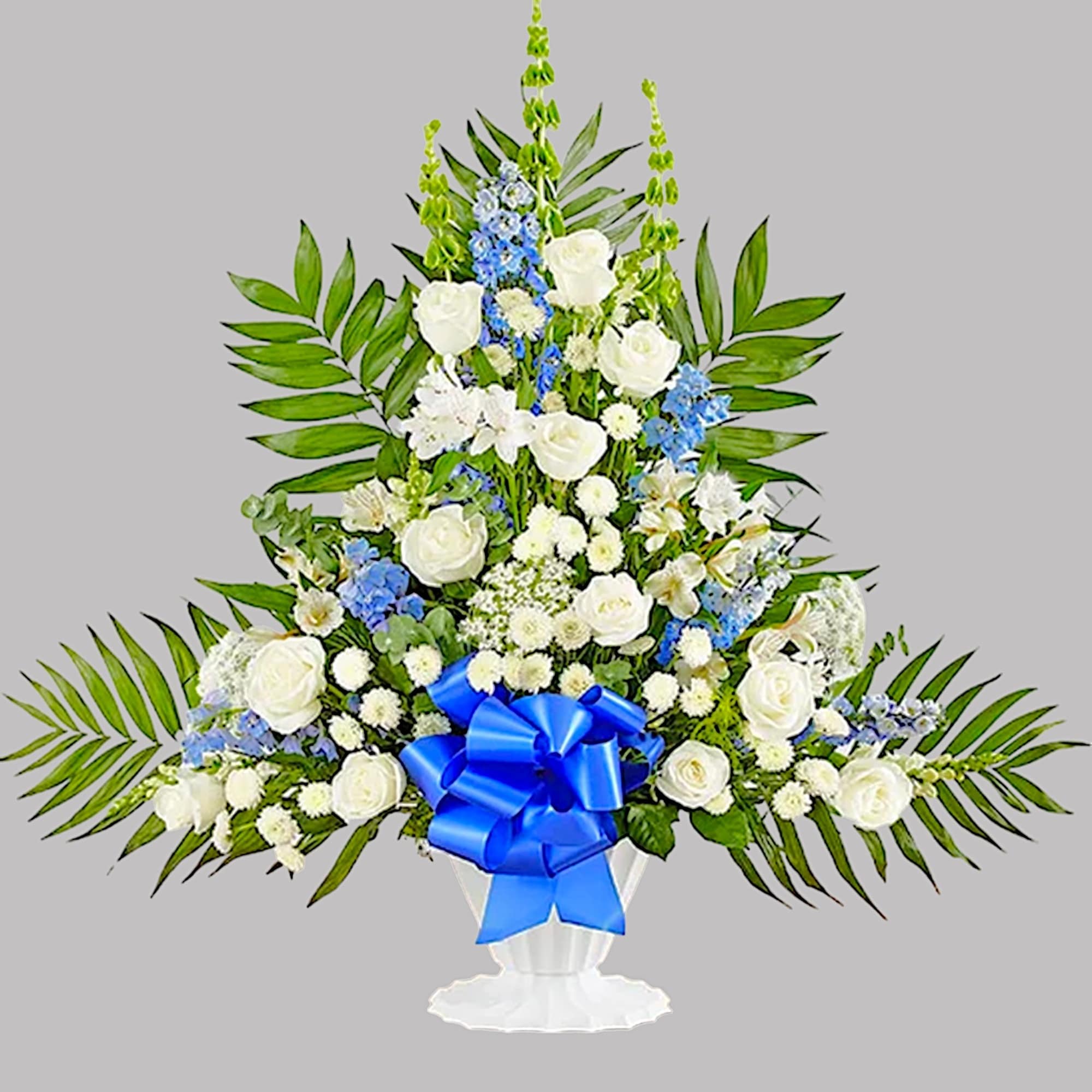 White roses and blue flowers in a white urn with a blue bow