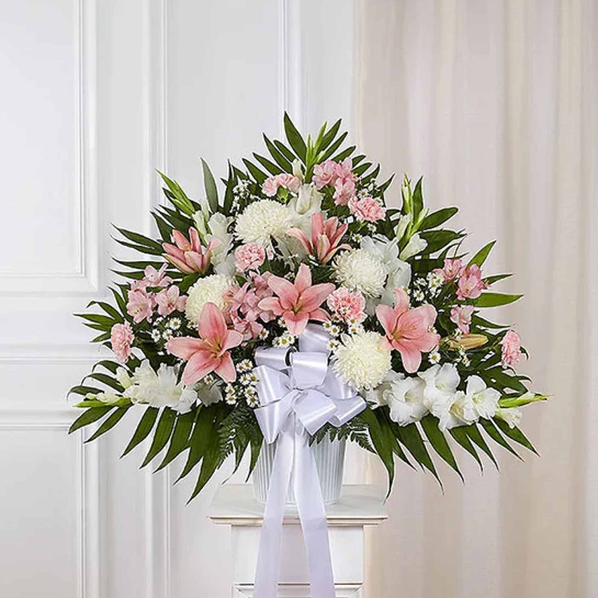 Pink and white floral spray with a white ribbon bow in a vase