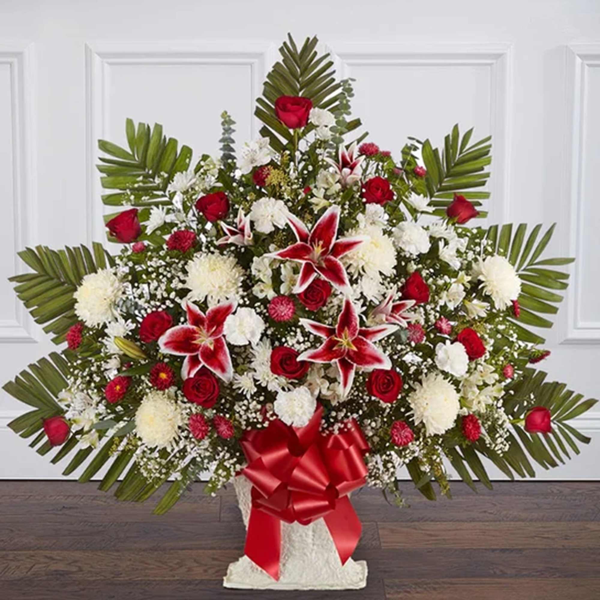 Large red and white floral spray with palm fronds and a red ribbon