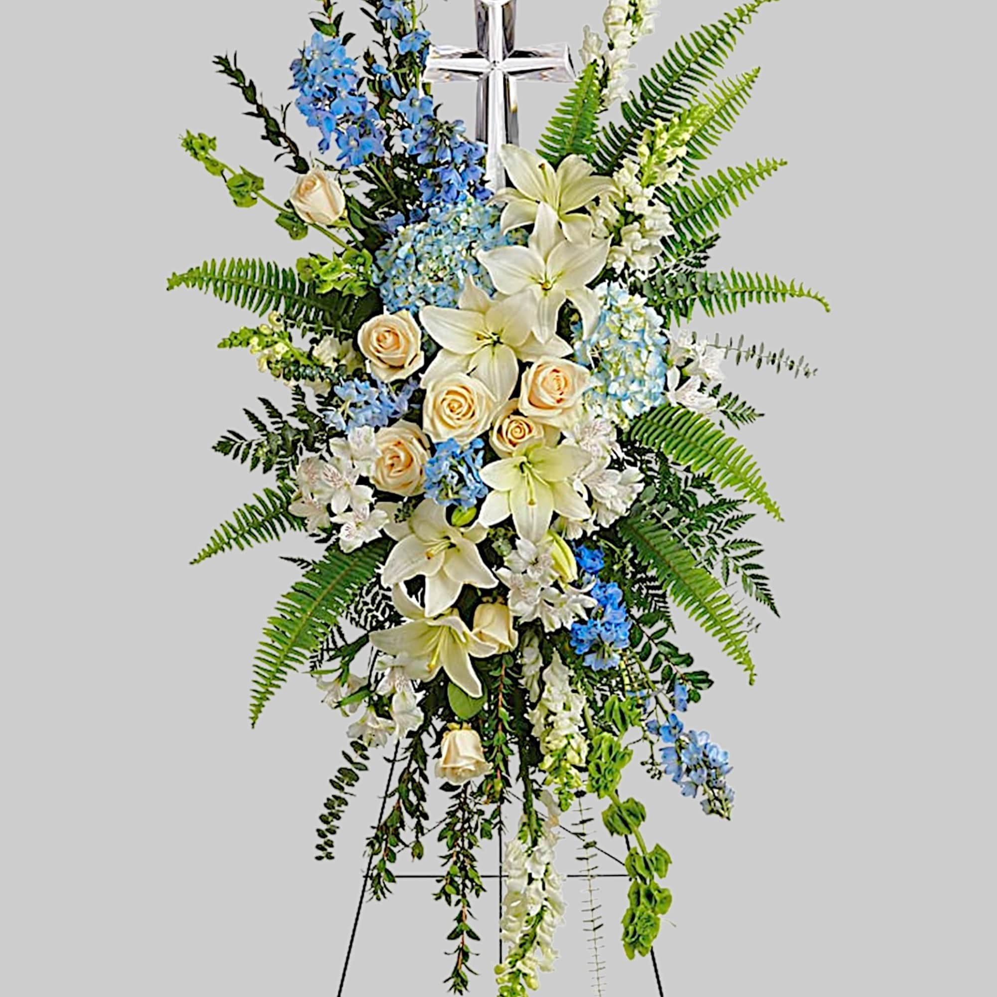 Standing floral spray with white lilies, cream roses, and blue flowers on an easel, photo 4 of 5