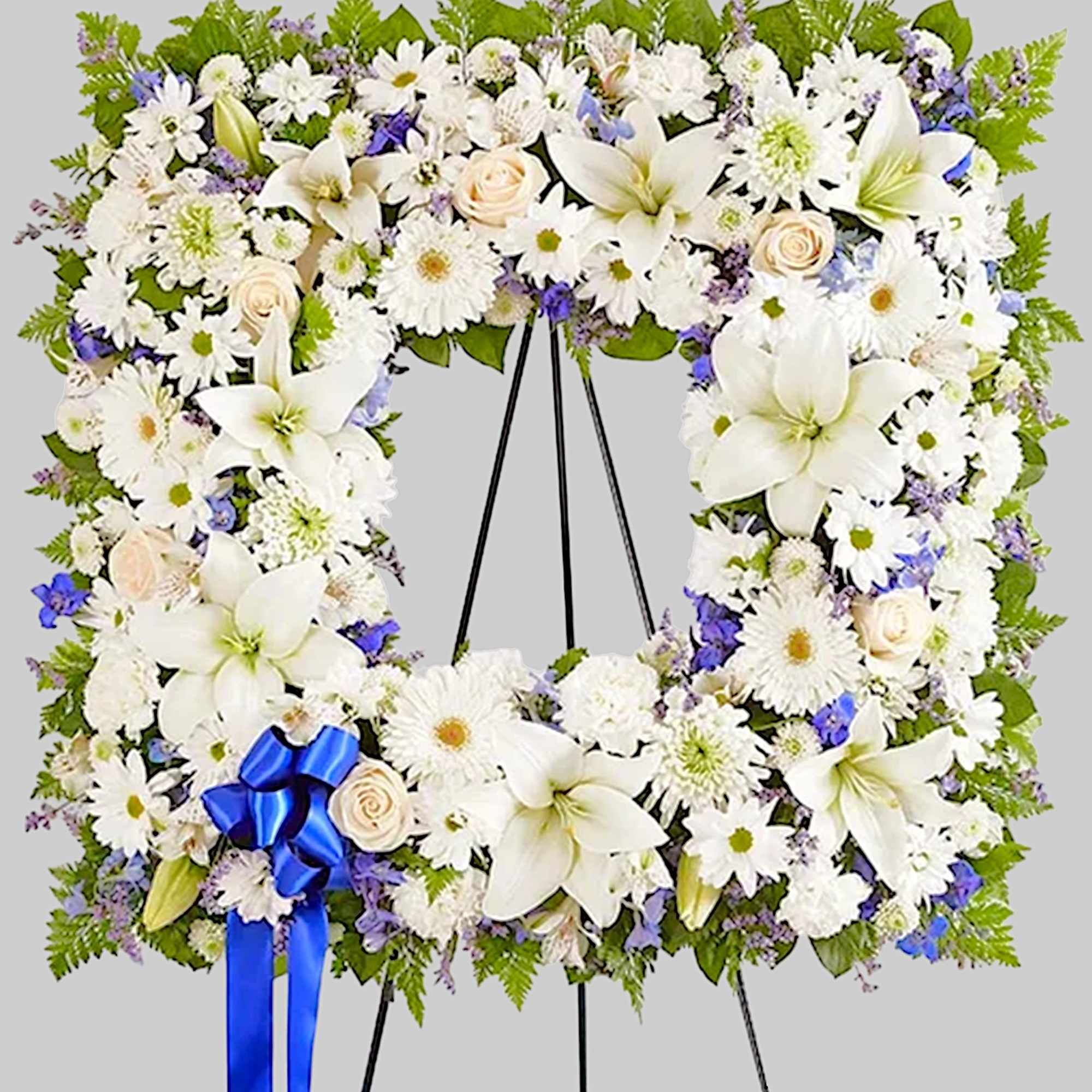 Large white floral wreath on a black easel with a blue ribbon