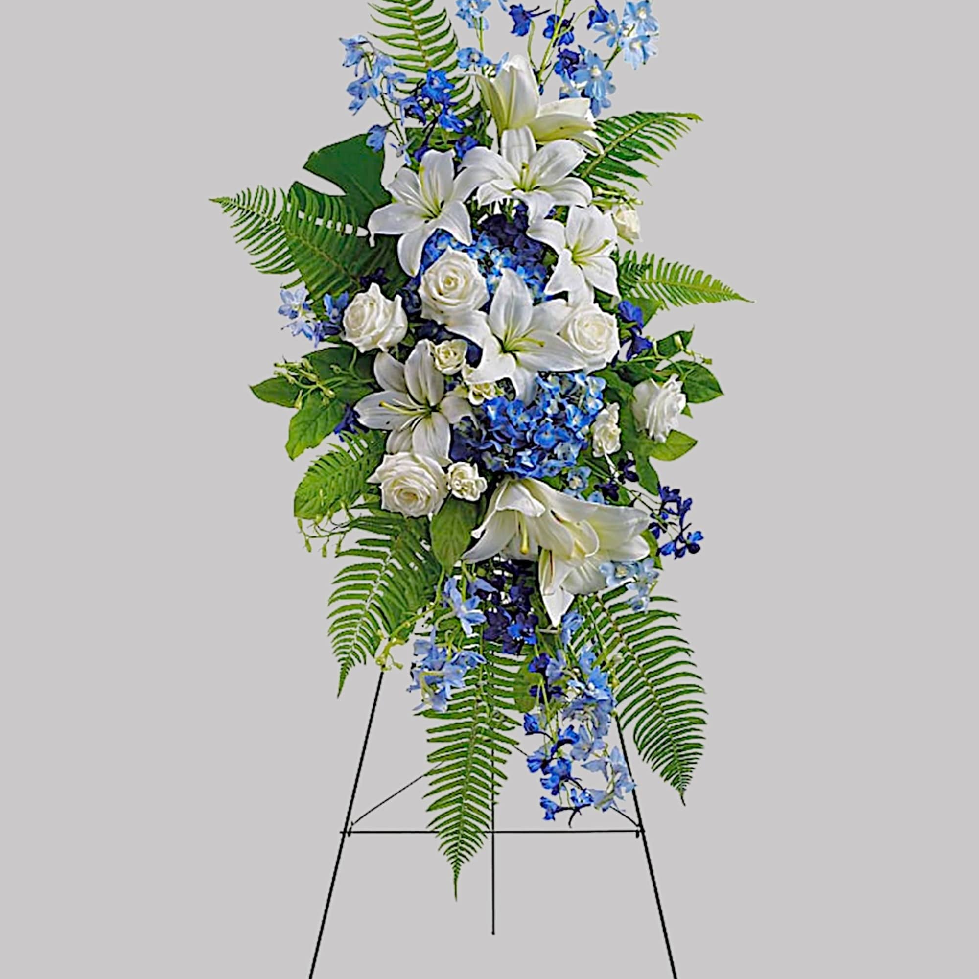 Standing floral spray with white lilies, white roses, and blue flowers