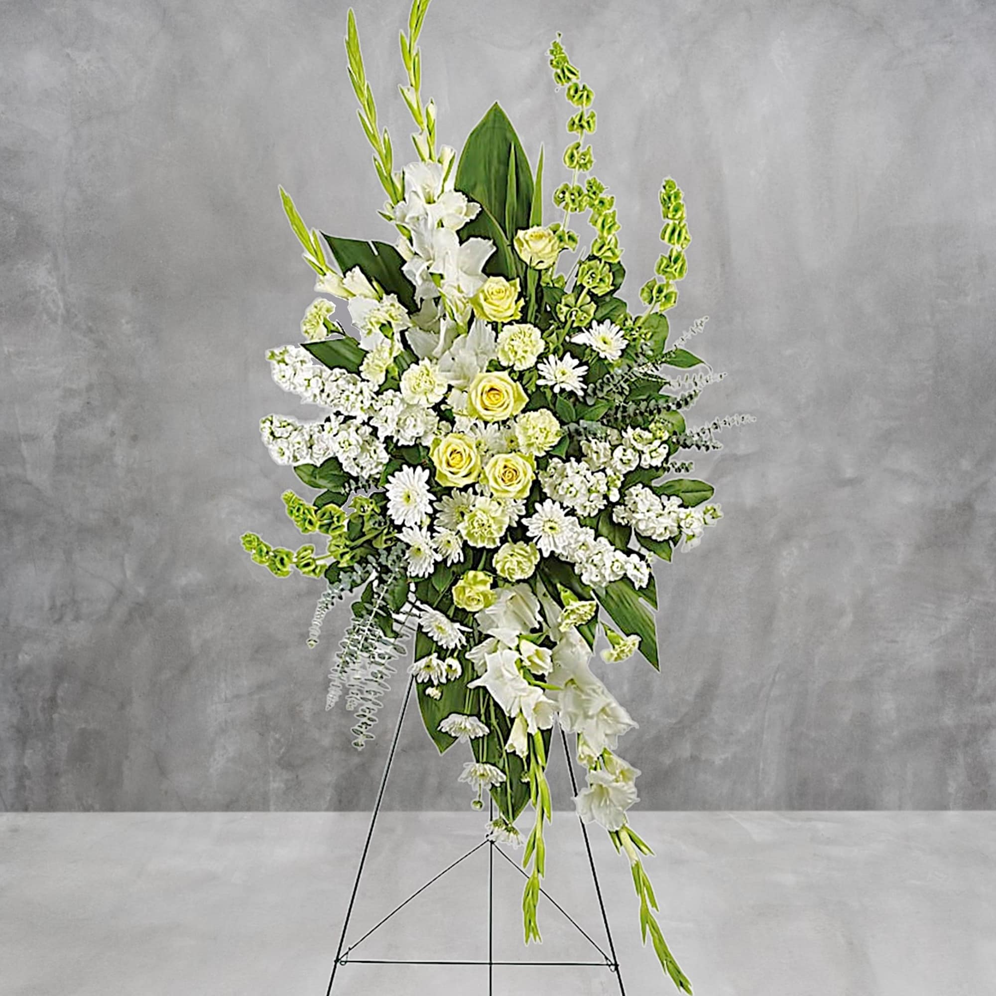 Tall white floral standing spray with yellow roses on a metal easel