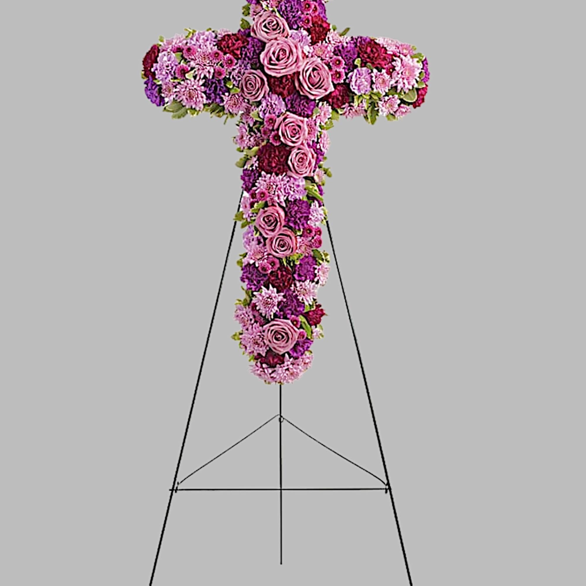 Cross-shaped floral tribute on a stand with pink and purple flowers