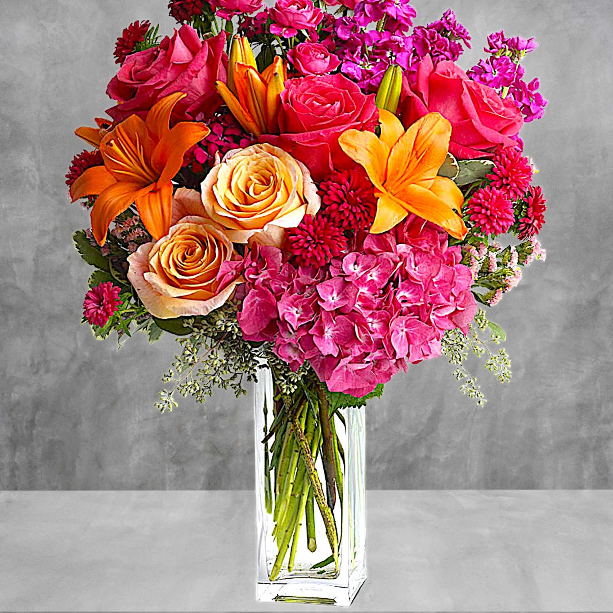 Bright mixed bouquet of roses, lilies, and pink hydrangeas in a clear vase, photo 2 of 4