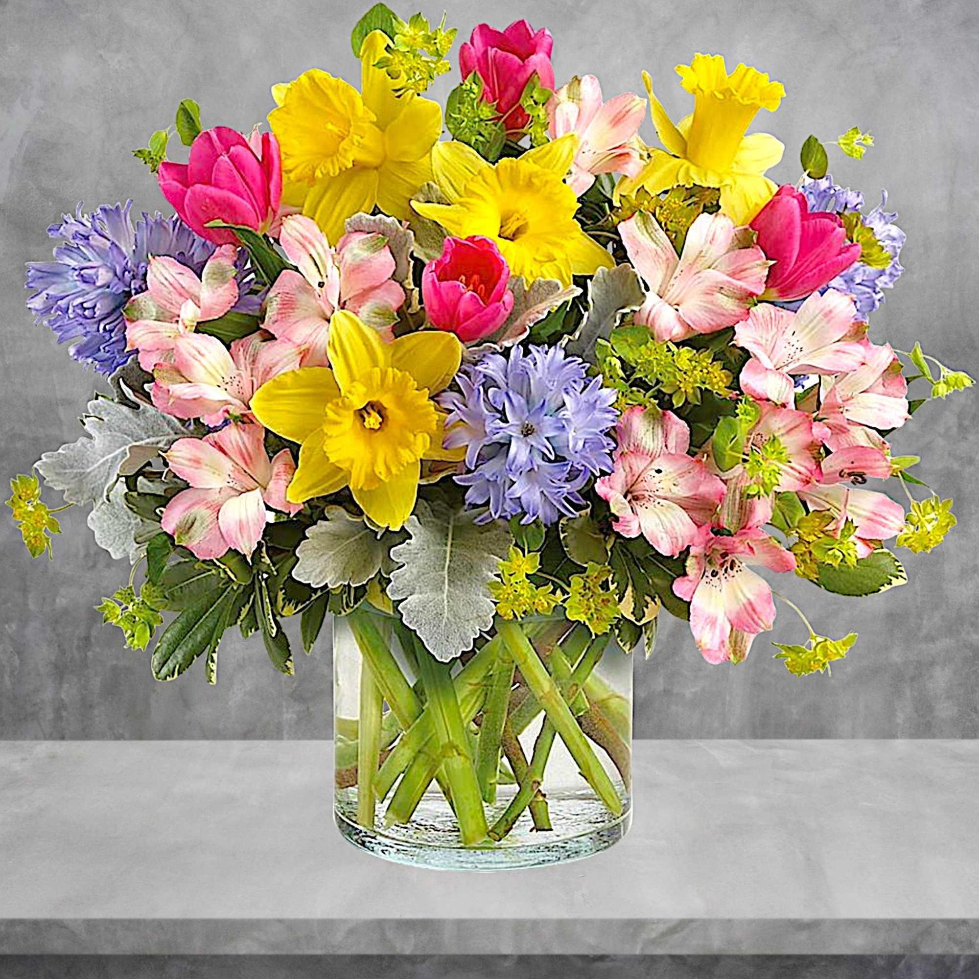 Colorful bouquet of tulips, daffodils, and alstroemeria in a clear glass vase