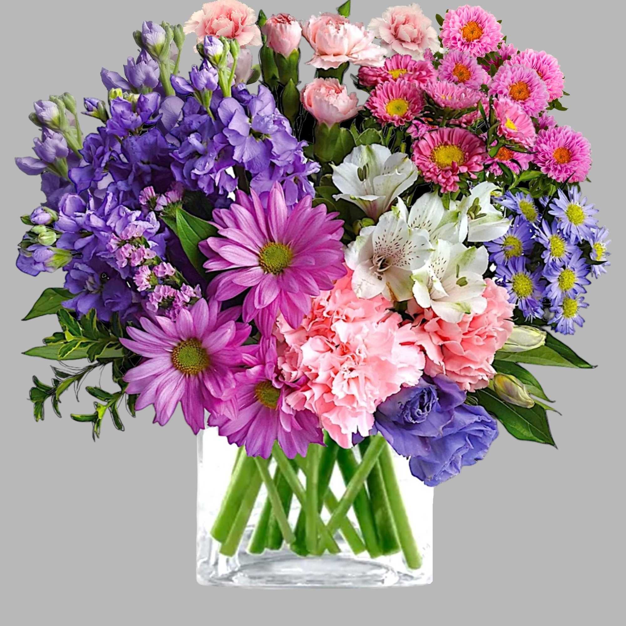 Mixed bouquet of purple, pink, and white flowers in a clear glass vase