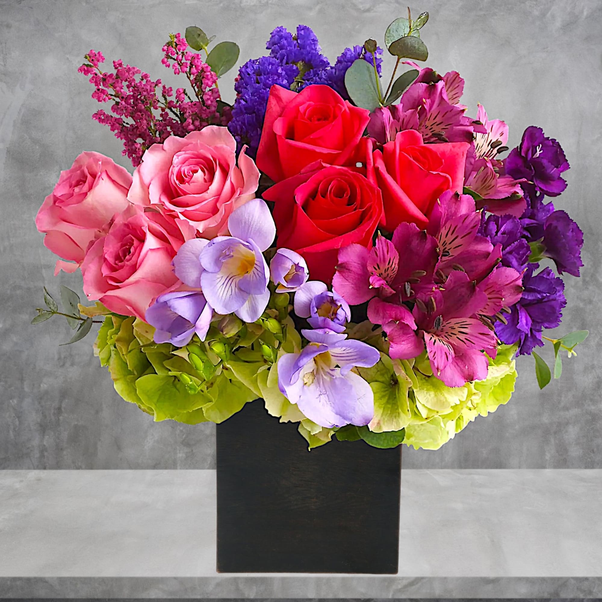 Colorful bouquet of roses, orchids, and hydrangeas in a black box
