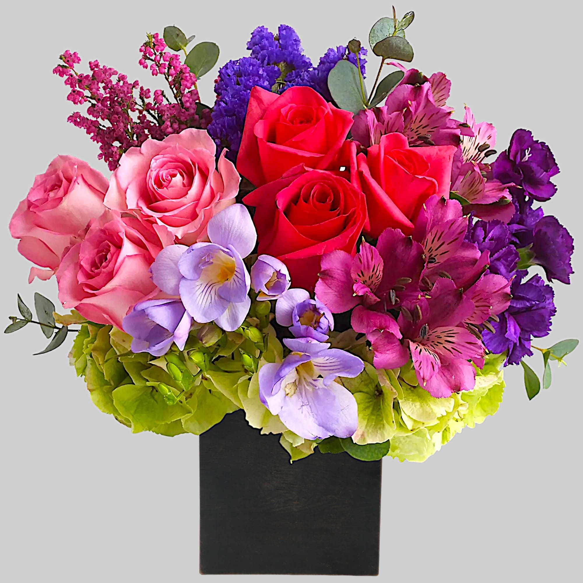 Colorful bouquet of roses, alstroemeria, and purple blooms in a black vase