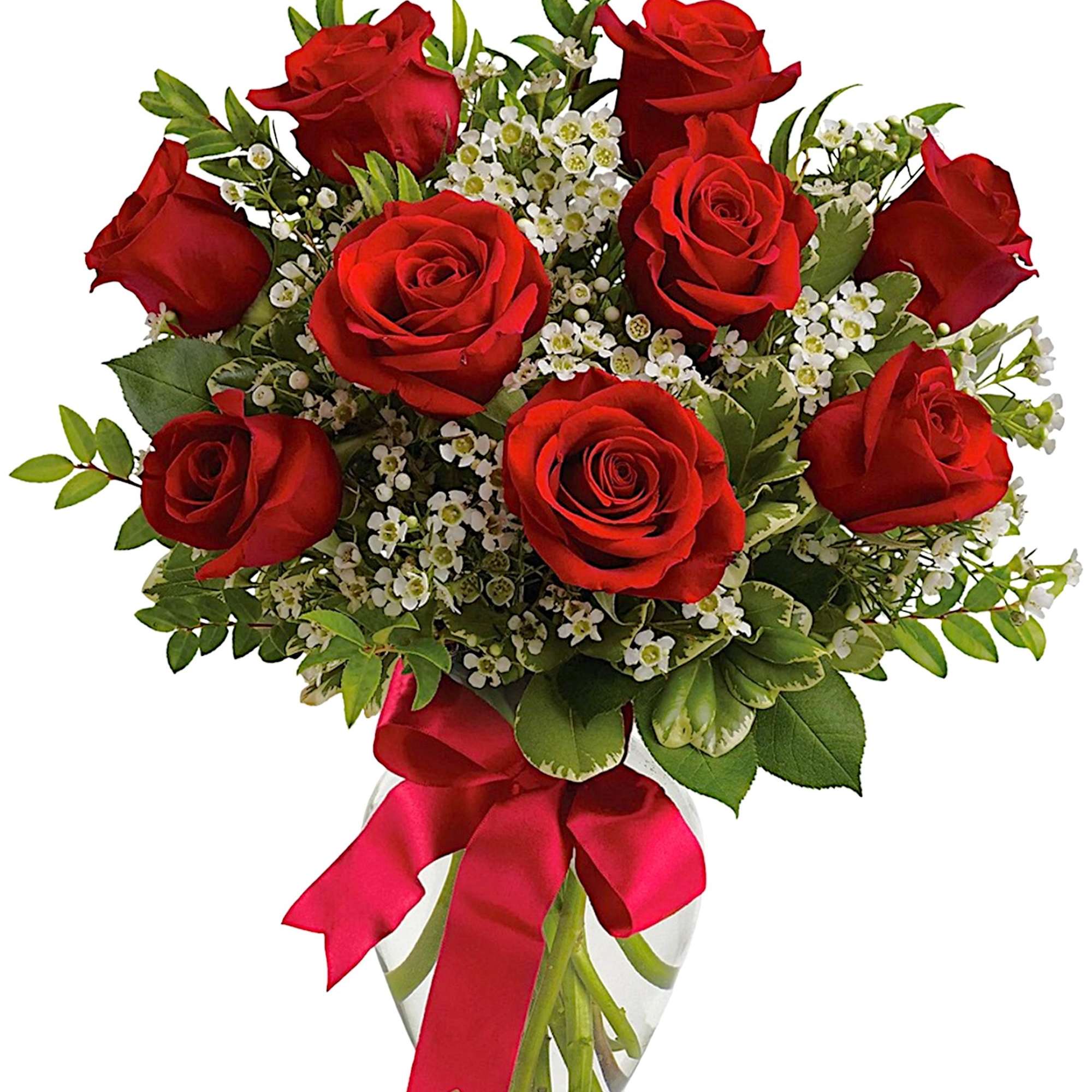 Red roses and white filler flowers in a clear glass vase with a red ribbon