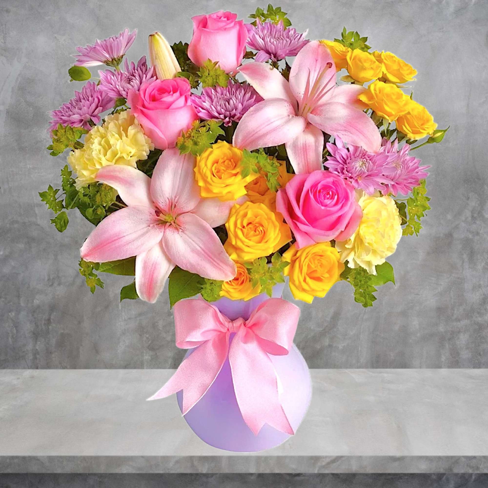 Pink lilies and roses in a lavender vase with a pink ribbon