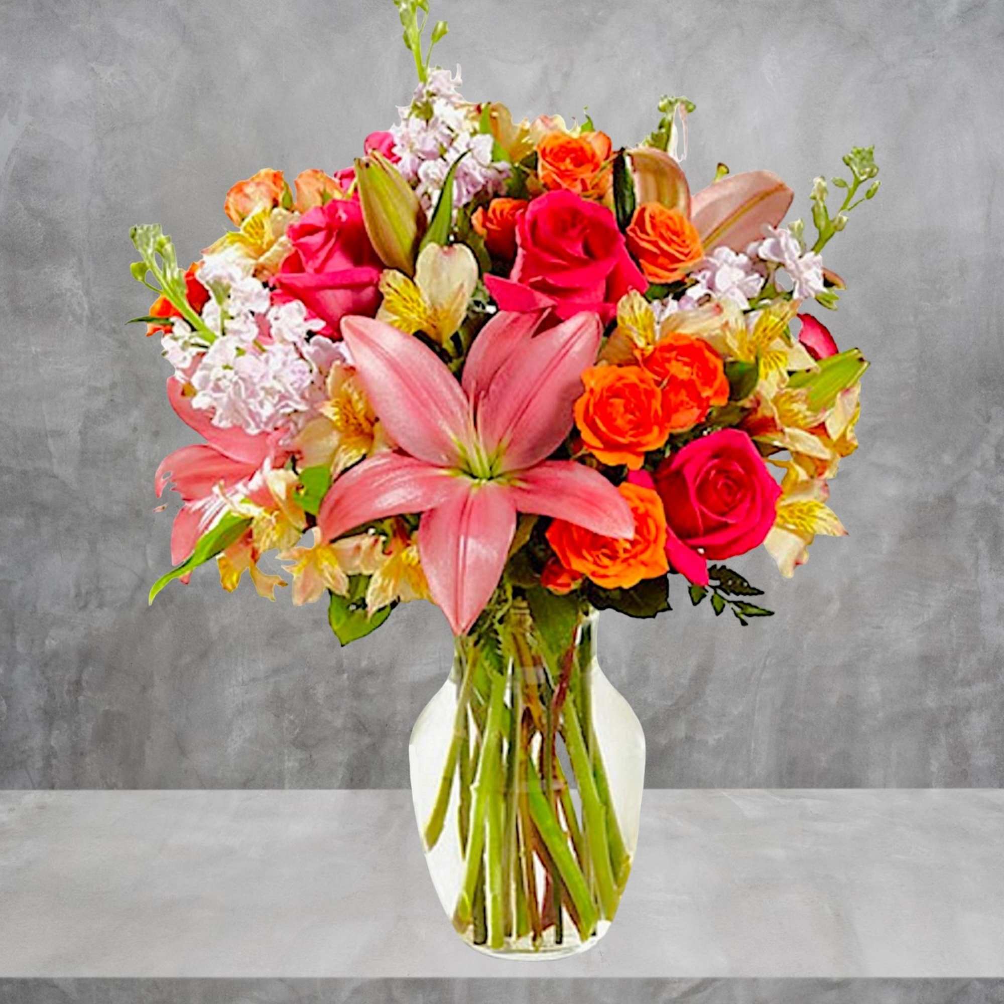 Mixed bouquet of pink lilies, roses, and orange flowers in a glass vase, photo 7 of 13
