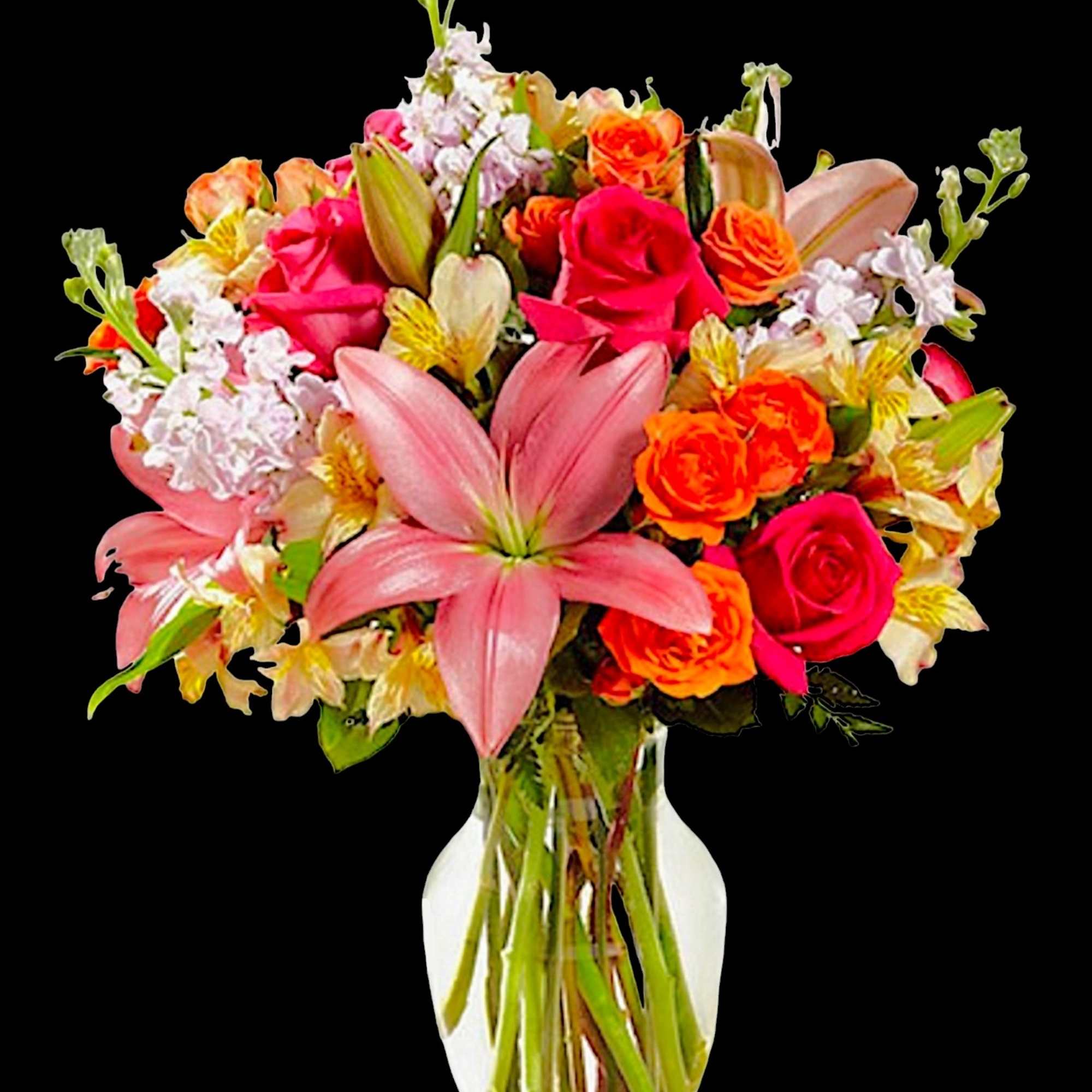 Mixed bouquet of pink lilies, roses, and orange flowers in a clear vase