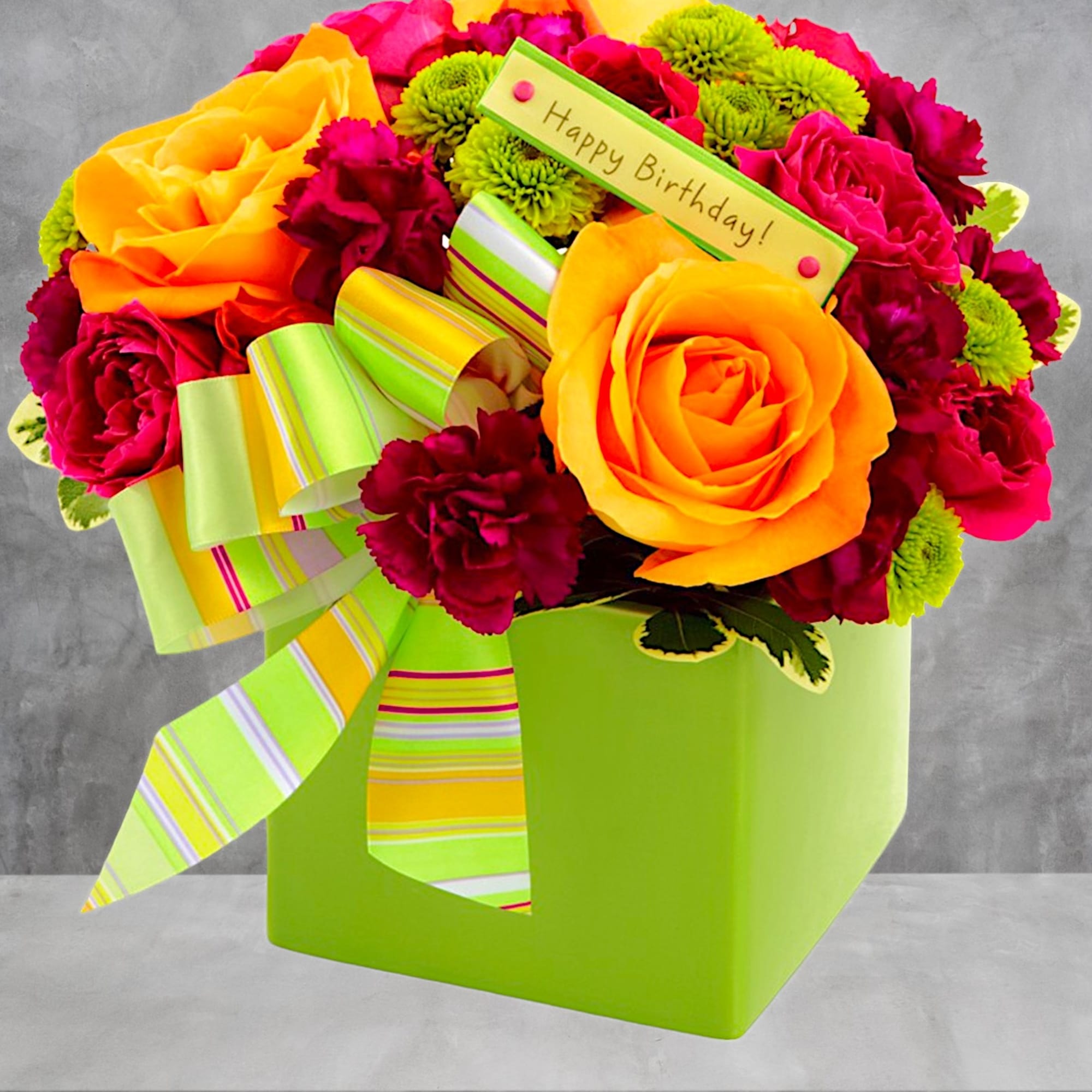 Bright bouquet of orange roses, magenta carnations, and green button mums in a lime box