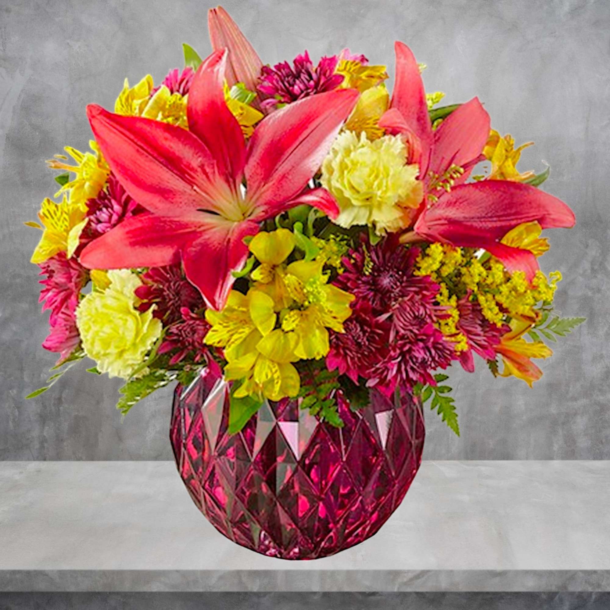 Bright mixed bouquet in a pink faceted vase with pink lilies and yellow flowers