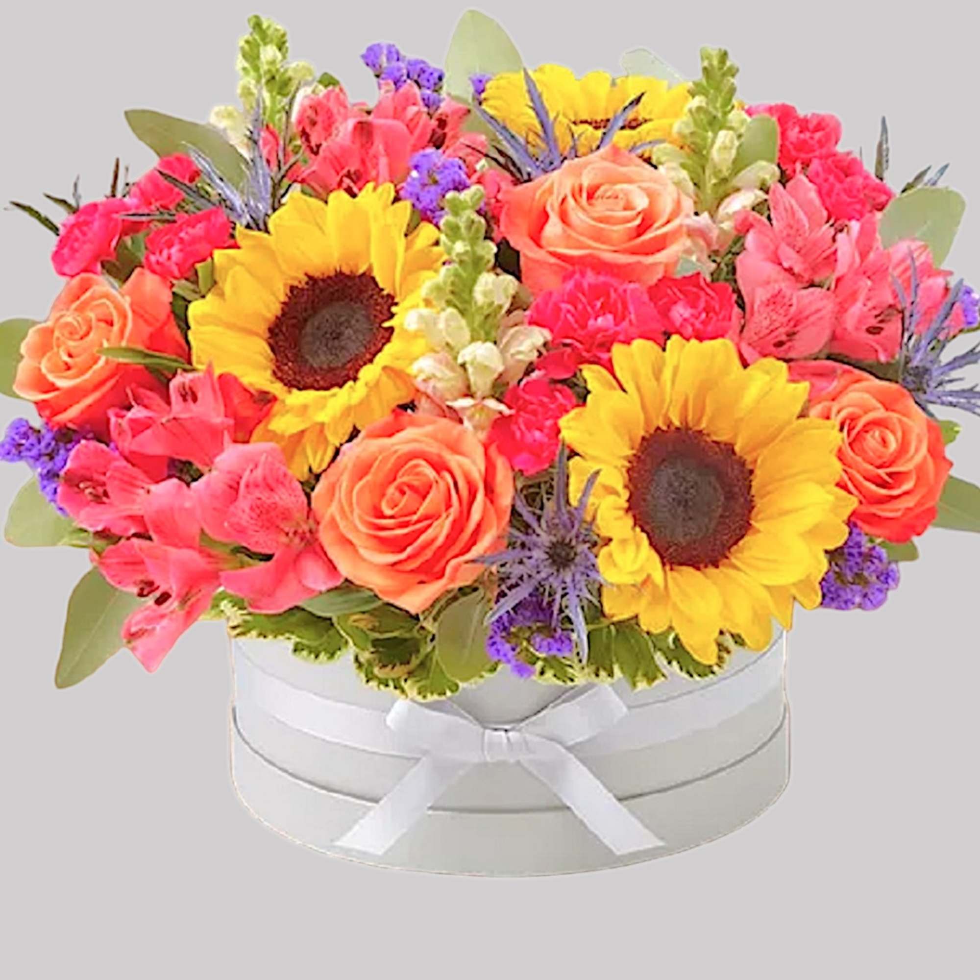 Bright mixed bouquet with sunflowers and roses in a white round box
