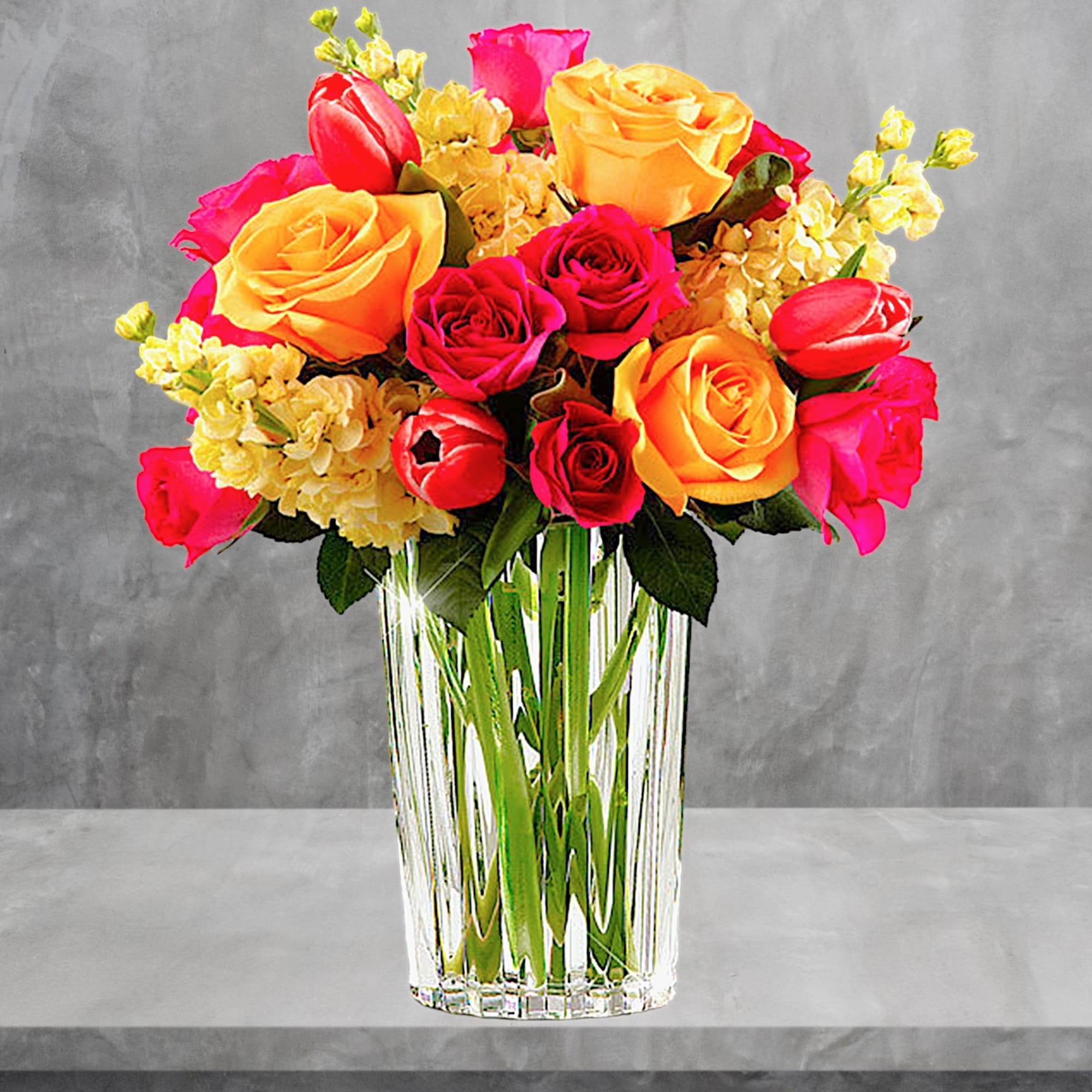 Bouquet of red, pink, and yellow roses in a clear glass vase